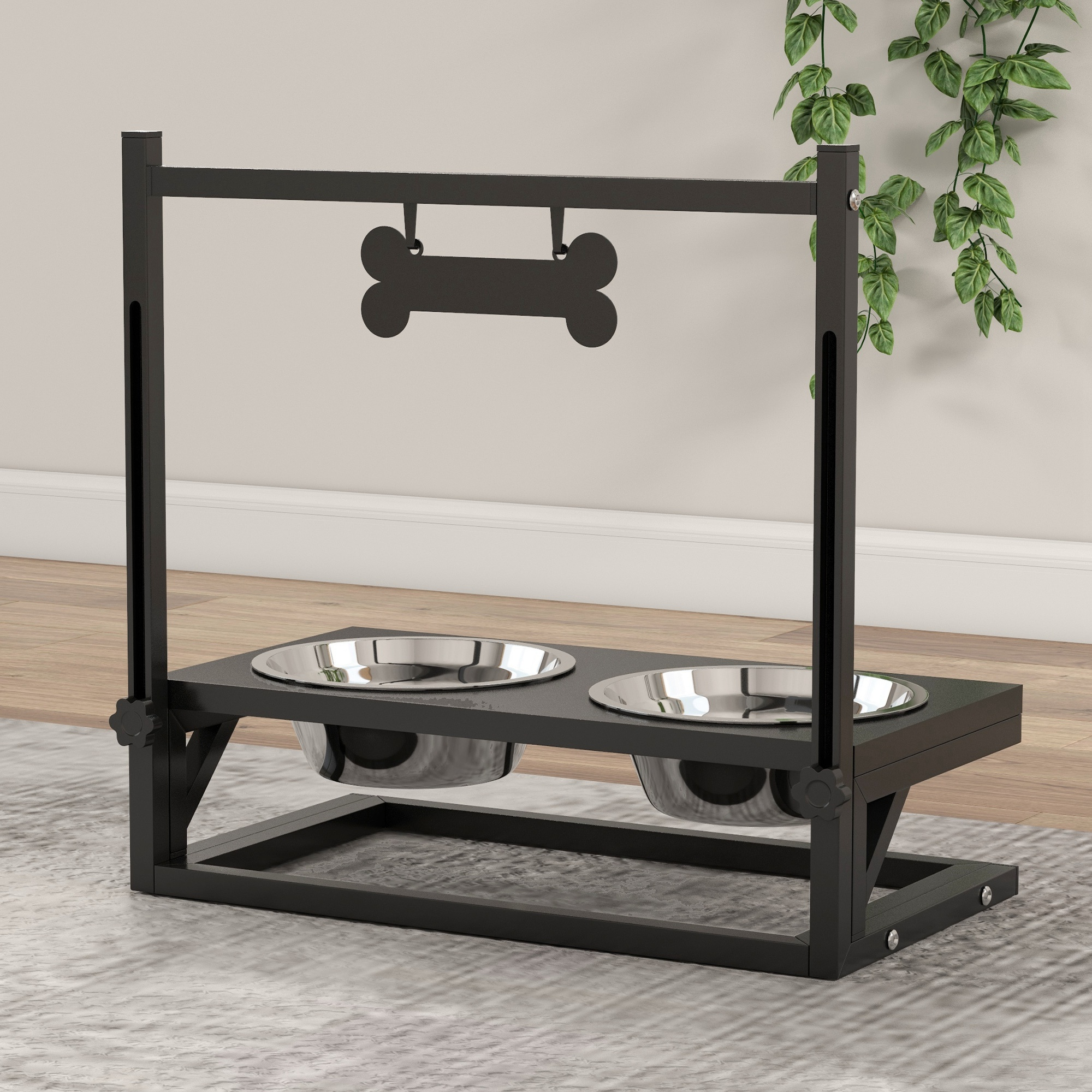 Un soporte negro de metal para cuencos para perros con dos cuencos de acero inoxidable. Un letrero con forma de hueso cuelga arriba. Planta verde en el fondo.