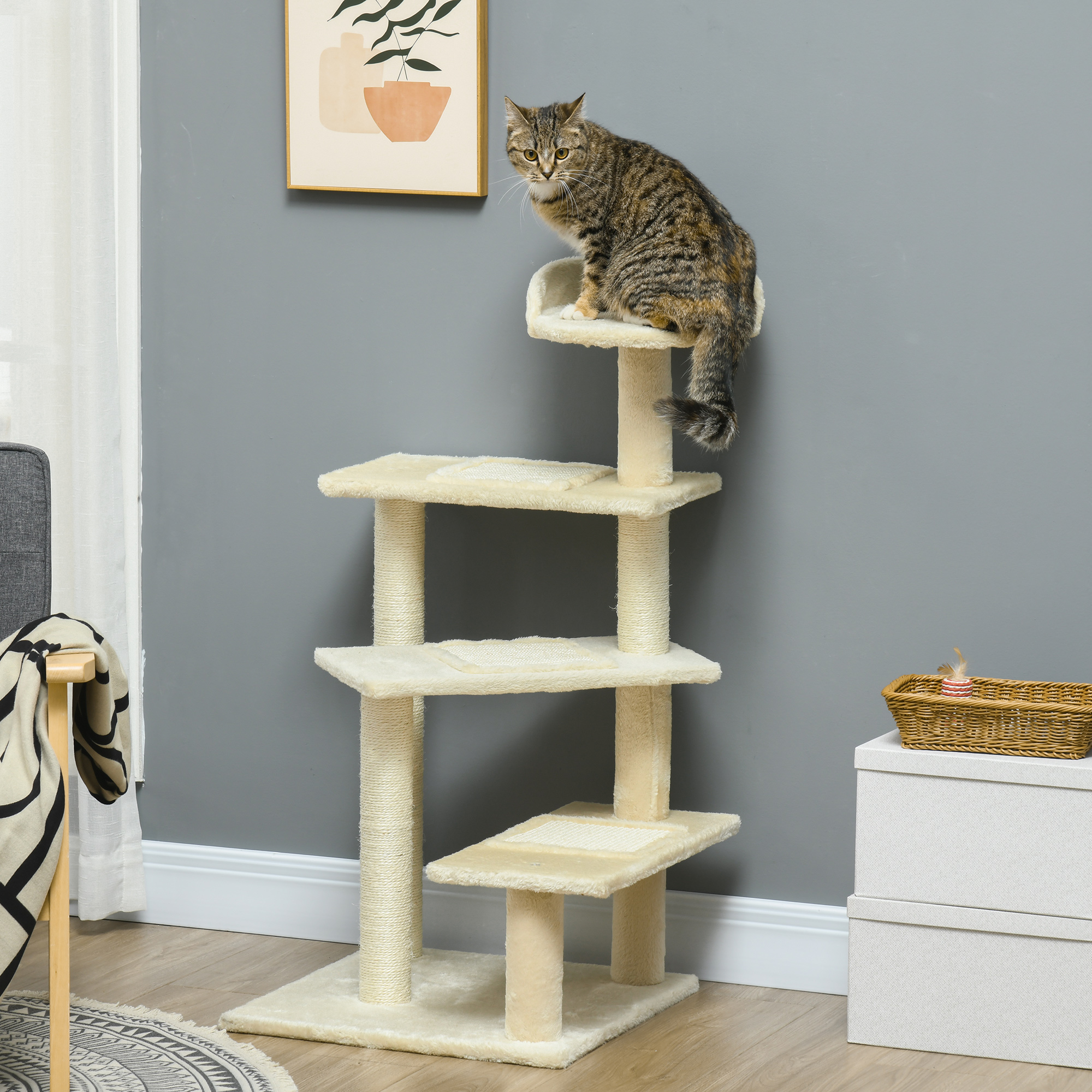 Un gato atigrado se sienta en un árbol para gatos. El árbol es beige, con plataformas y postes para rascar. Un cuadro cuelga en la pared gris.