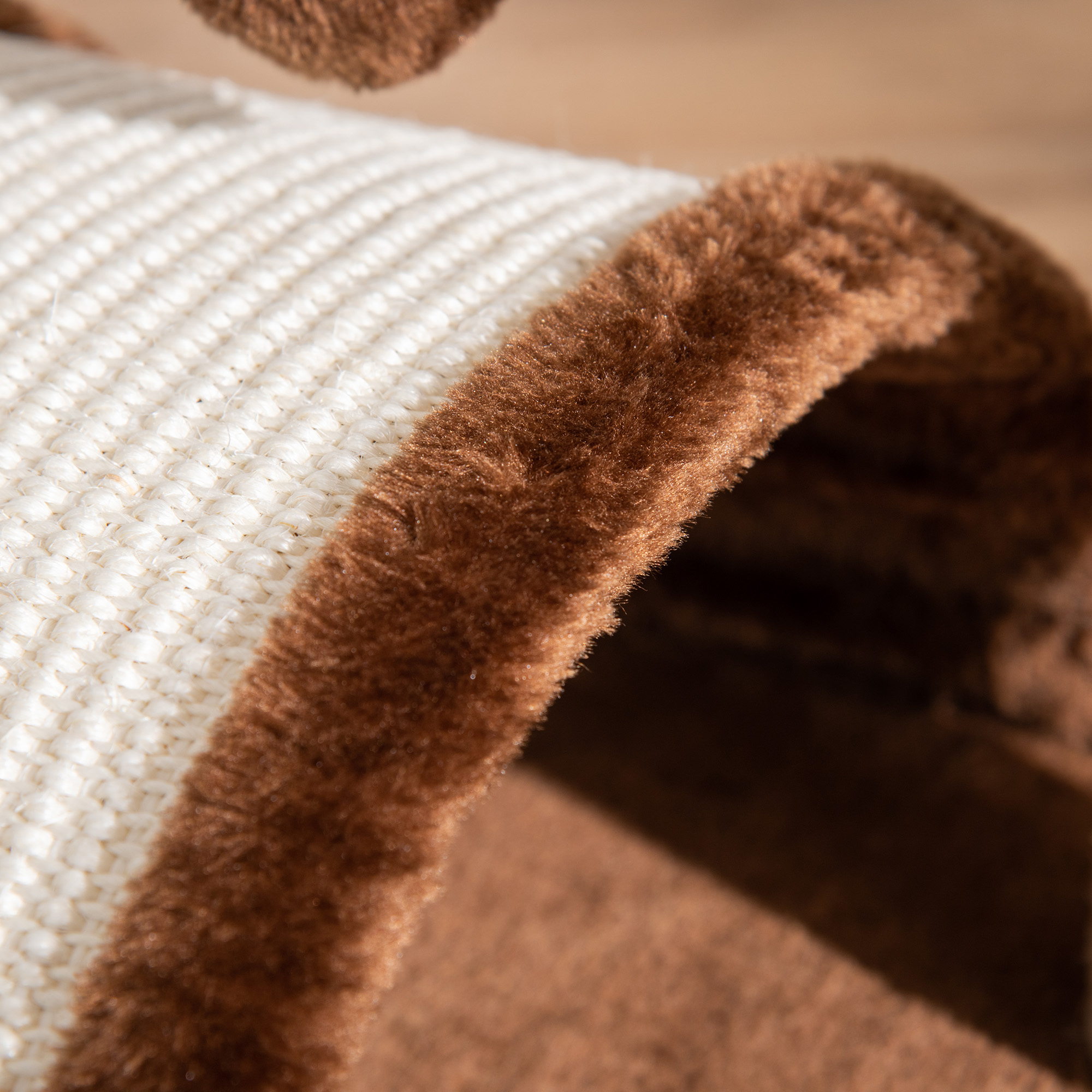 Primer plano de un rascador para gatos. Material beige tejido con bordes marrones y esponjosos. Fondo de superficie de madera.