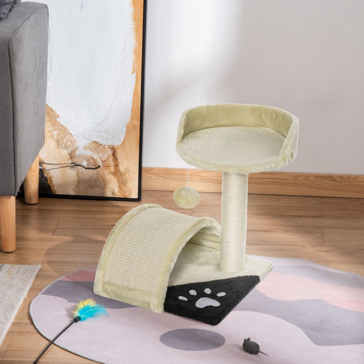 Árbol para gatos con una percha y un túnel. Un juguete para gatos y un ratón de juguete están en el suelo. Fondo: una pintura, una silla y una alfombra.