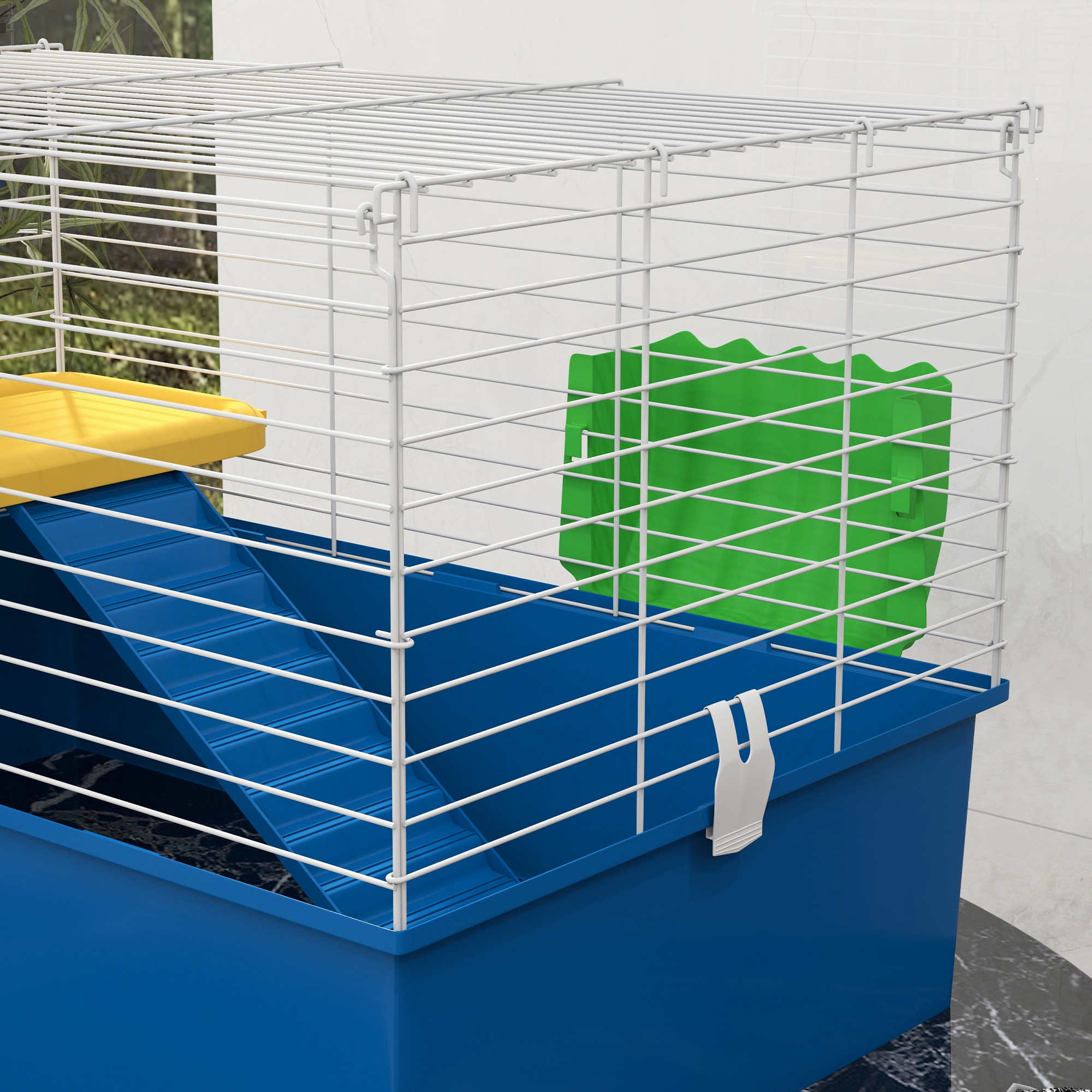 Una jaula azul y blanca con una plataforma amarilla, una rampa azul y un objeto verde dentro. El fondo es una pared alicatada.