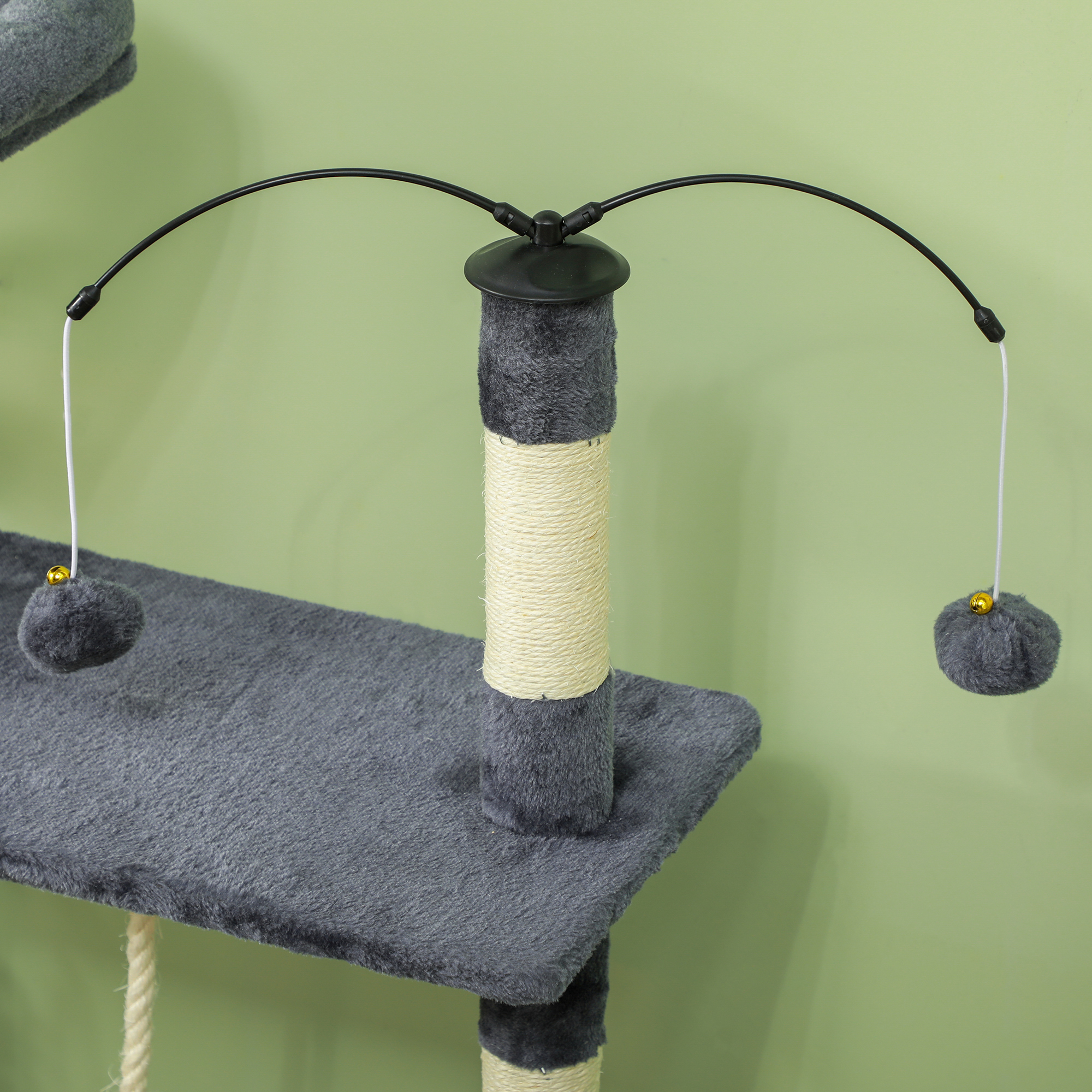 Árbol para gatos con plataformas grises, un poste central envuelto en cuerda y juguetes colgantes. Fondo verde.