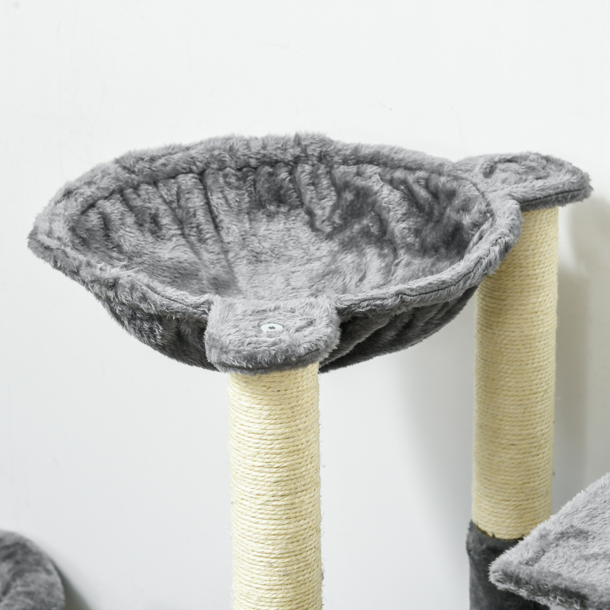 Árbol para gatos con plataformas de felpa gris y postes para rascar. El fondo es una pared blanca.