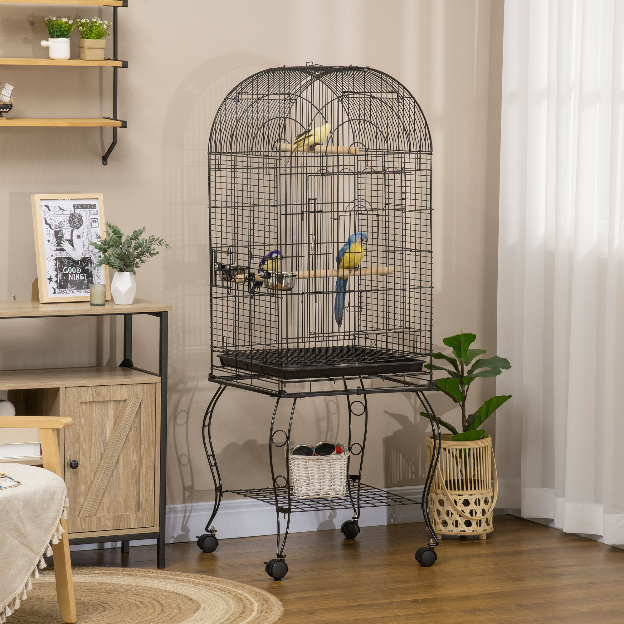Una jaula negra con tres pájaros dentro, colocada sobre un soporte rodante. Un armario, estanterías y una ventana con cortinas están en el fondo.