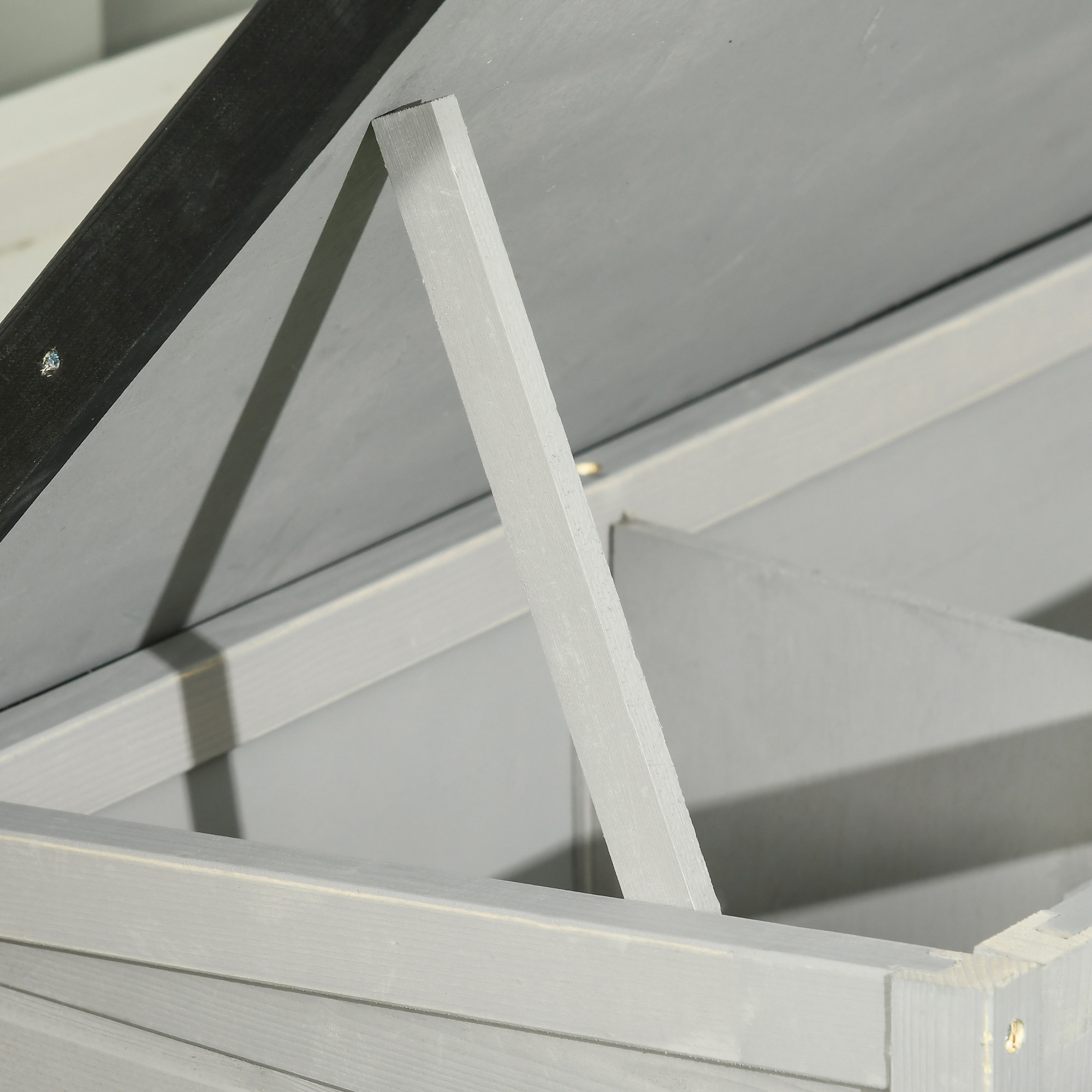 Primer plano de una estructura de madera gris con una viga de soporte. El techo es negro. La imagen se centra en los detalles de la construcción.