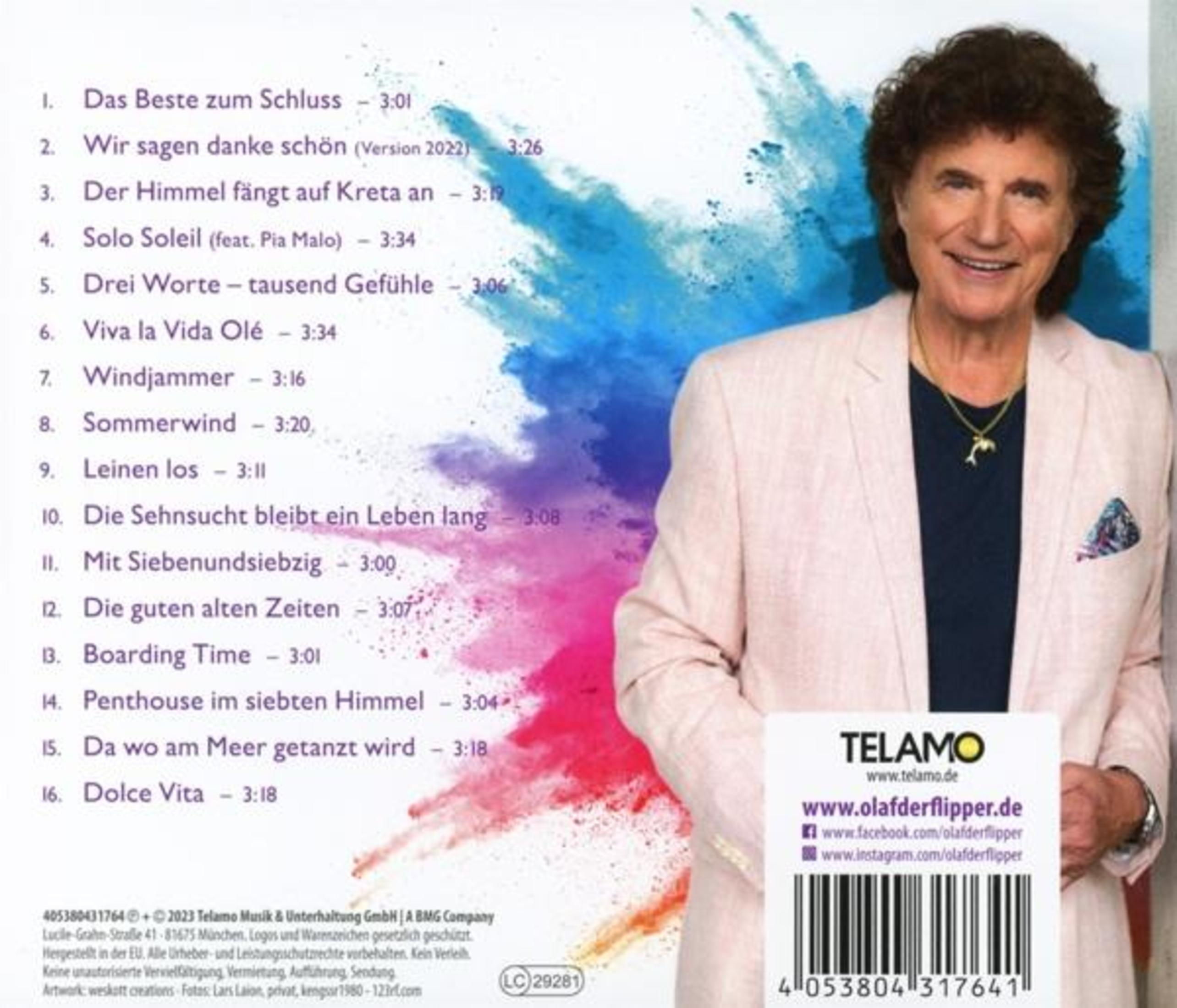 Mann lächelt, trägt rosa Jacke, blaues Hemd und Delphin-Halskette. Hintergrund mit blauem und pinkfarbenem Farbspritzer.