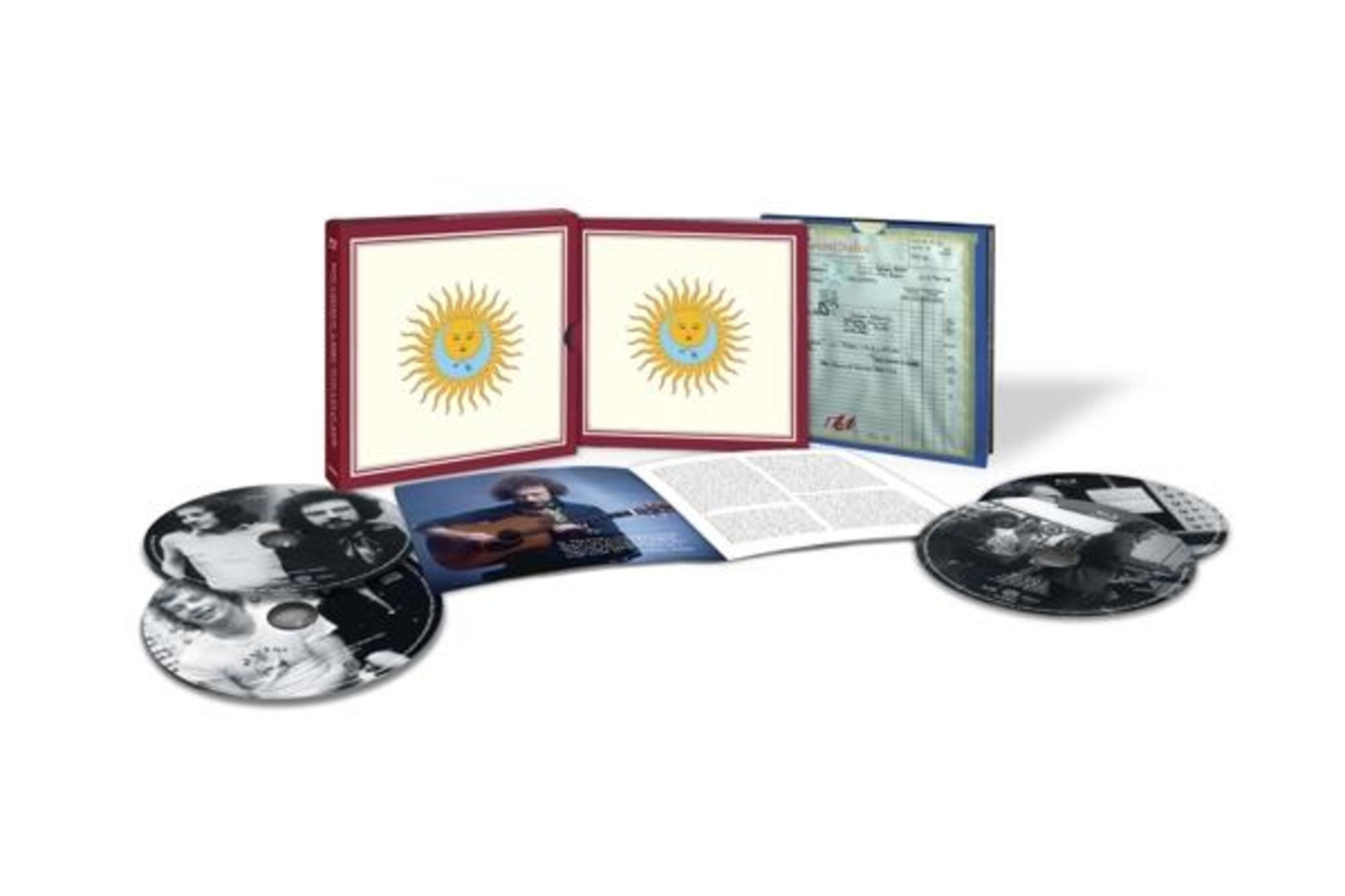 Ein Box-Set mit CDs, einem Booklet und Album-Cover. Zwei Boxen mit sonnenartigen Designs sind sichtbar.
