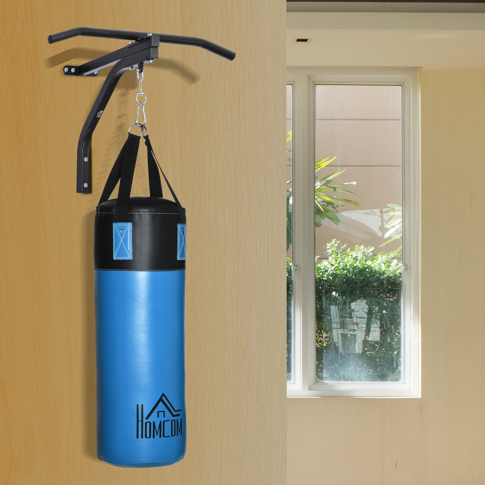Un saco de boxeo azul y negro cuelga de una barra de dominadas montada en la pared. Una ventana y vegetación al fondo.