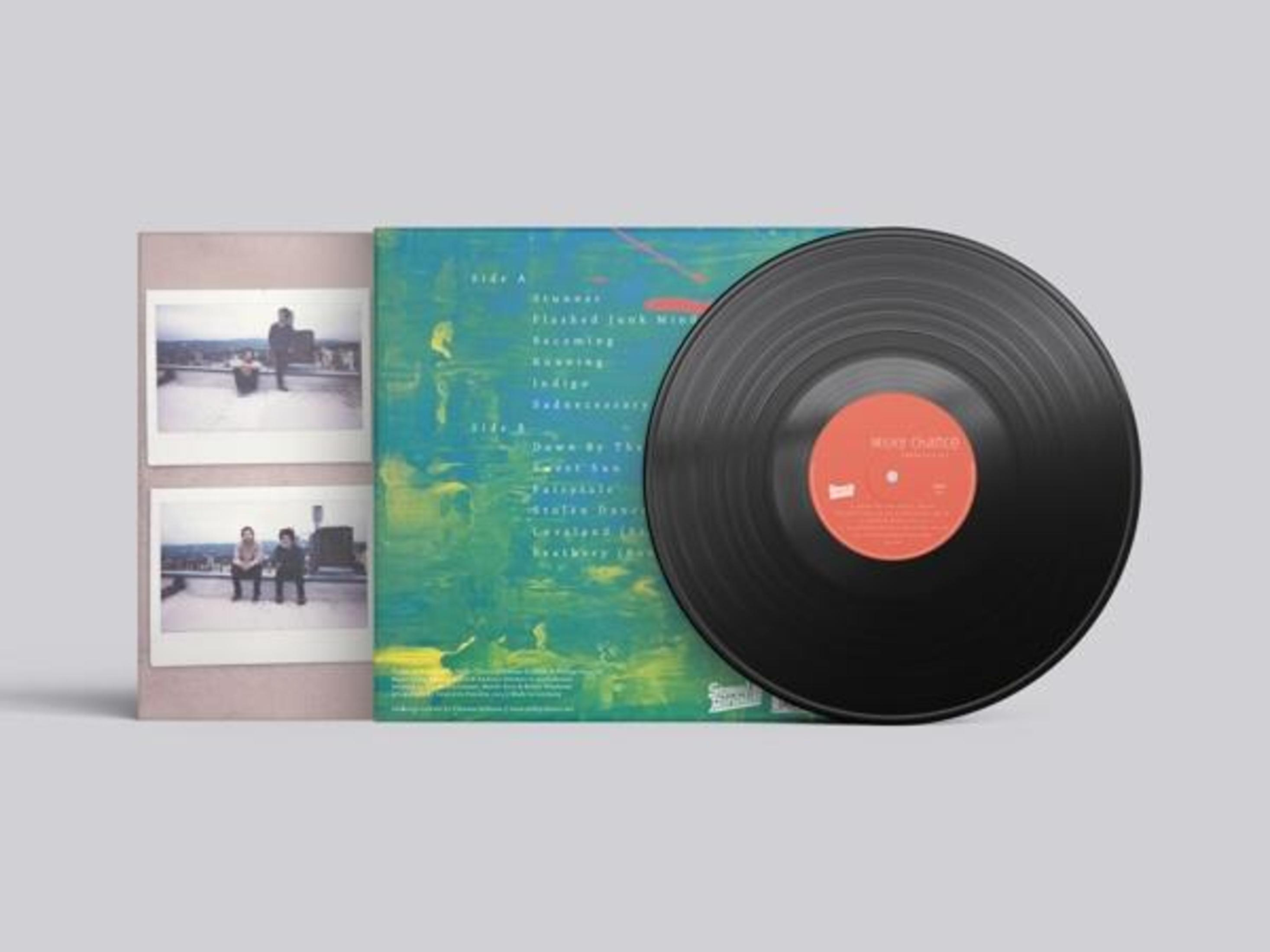 Copertina dell'album con un disco in vinile, grafica dell'album e due foto. Il disco è nero con etichetta rossa. La grafica è blu e verde.