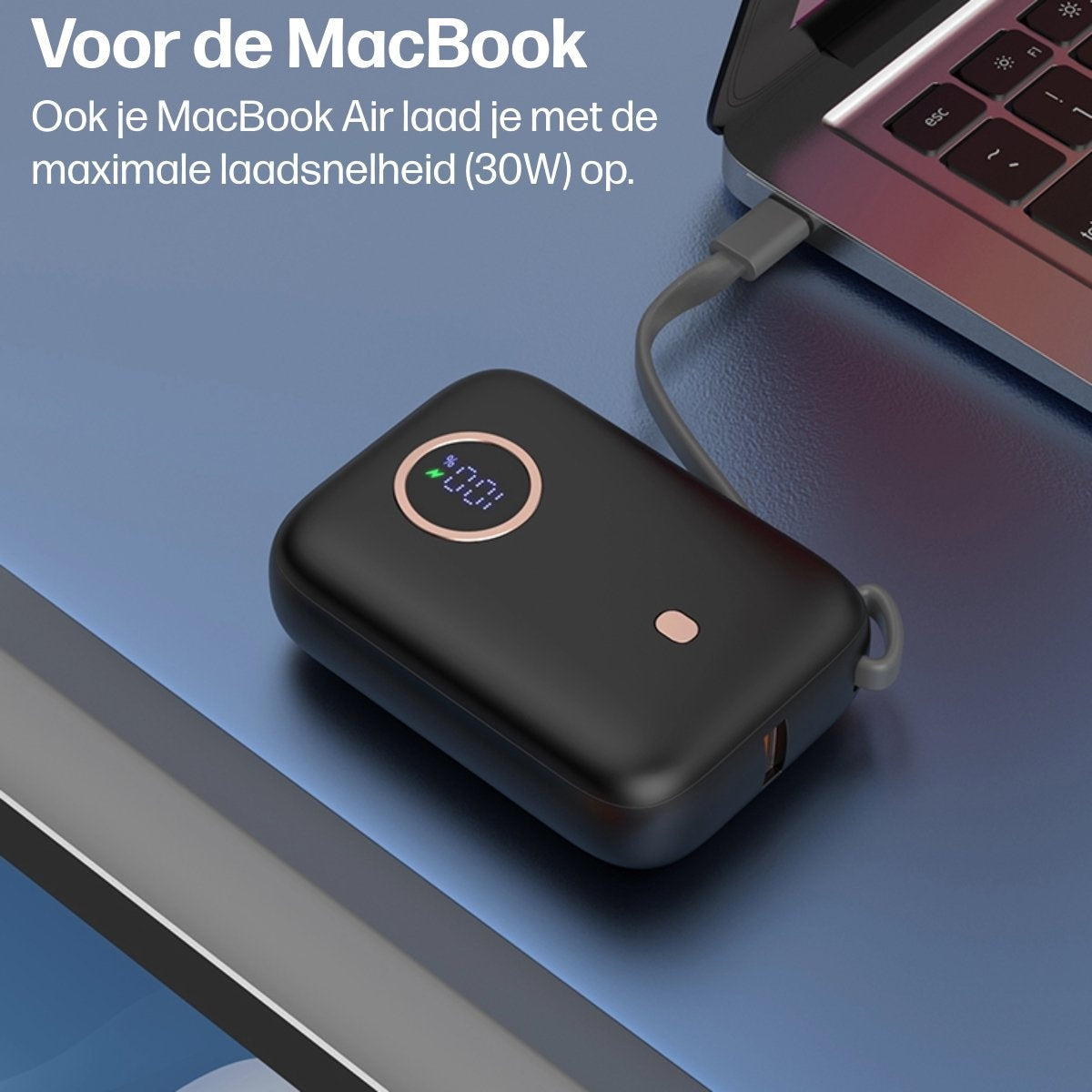 Een zwarte powerbank is met een kabel aan een laptop verbonden. De powerbank toont 100% lading.