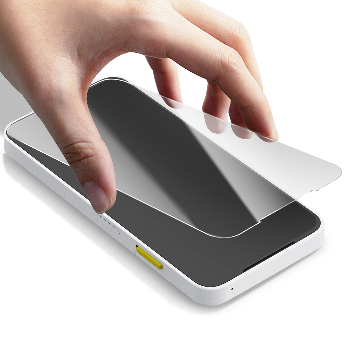 Een hand plaatst een schermbeschermer op een witte telefoon. De telefoon heeft een zwart scherm en een gele knop.