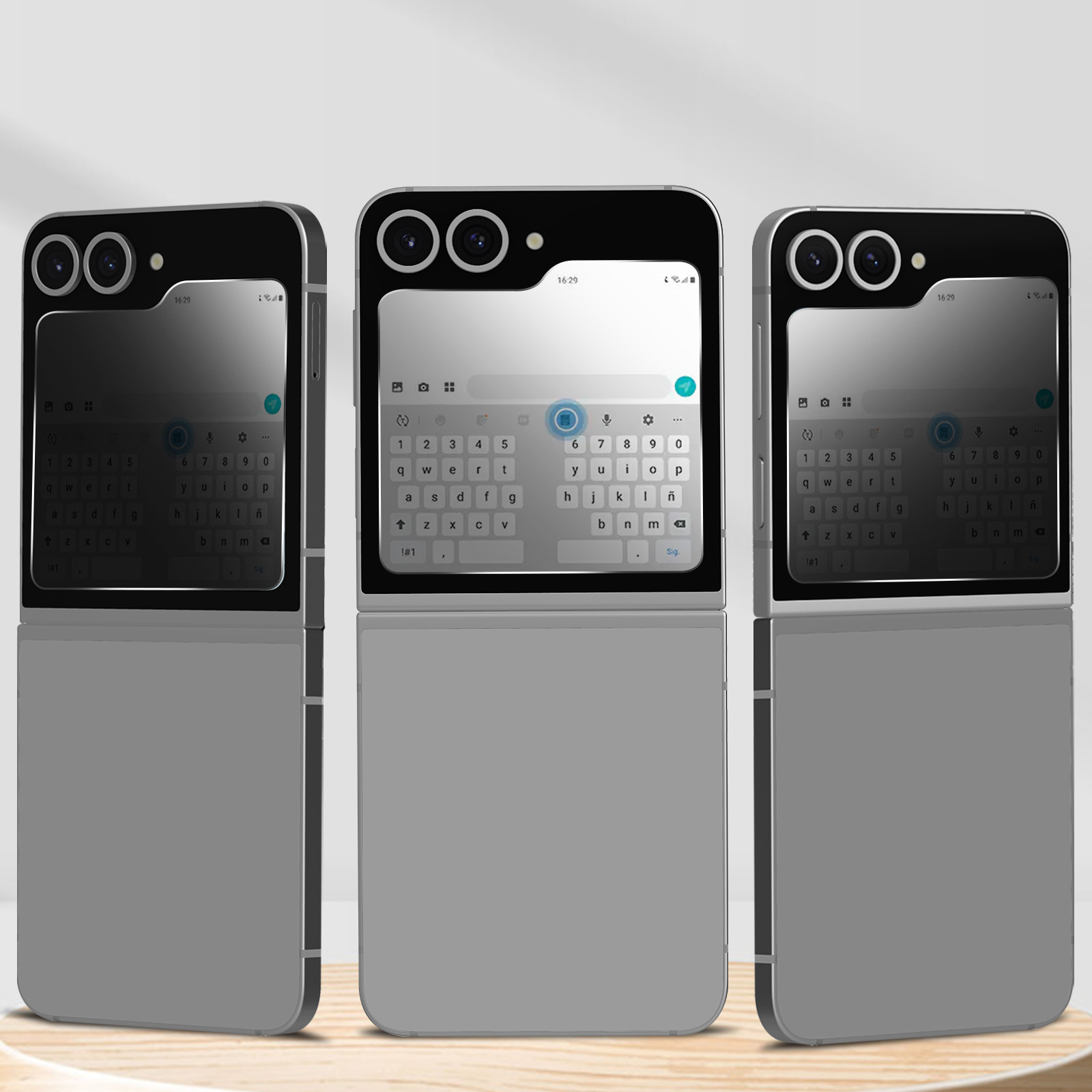 Tre telefoni grigi pieghevoli su una superficie di legno, ognuno con una tastiera.