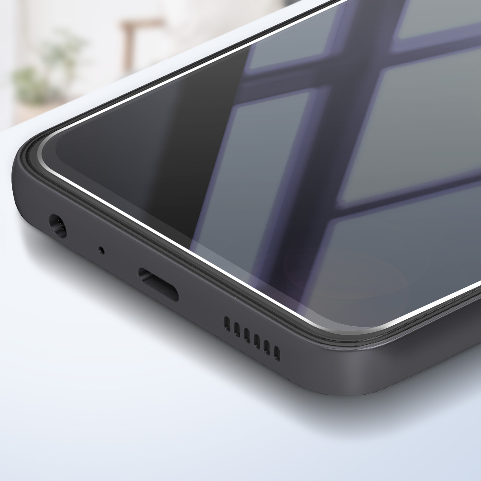 Primo piano di uno smartphone nero. Lo schermo riflette una finestra. Il telefono è su una superficie bianca.