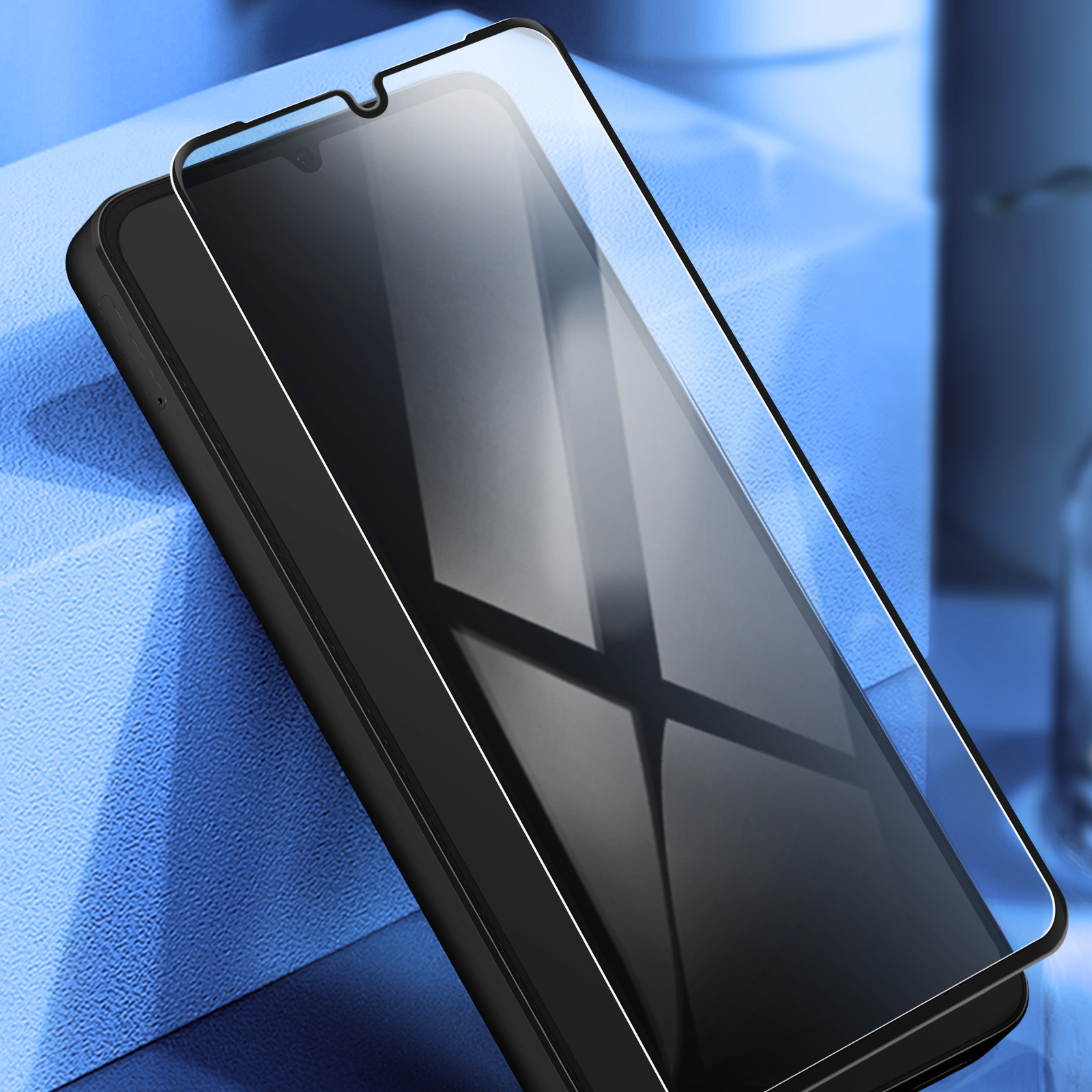 Uno smartphone nero con protezione schermo su una superficie blu. Il telefono è angolato, mostrando lo schermo e la protezione.