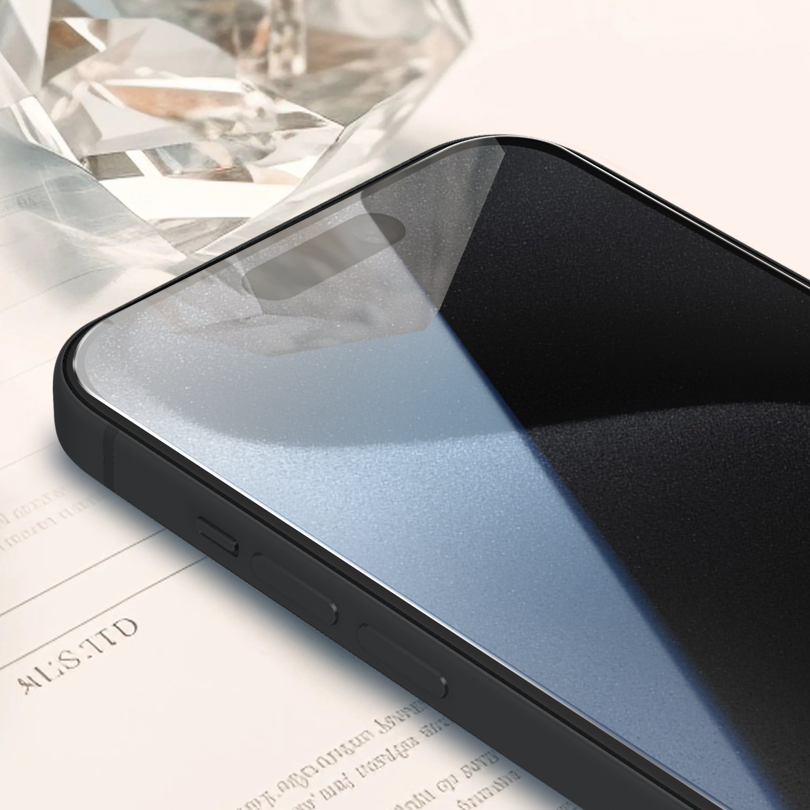 Primo piano di uno smartphone nero con schermo in vetro, appoggiato su carta con testo e una forma di cristallo sullo sfondo.