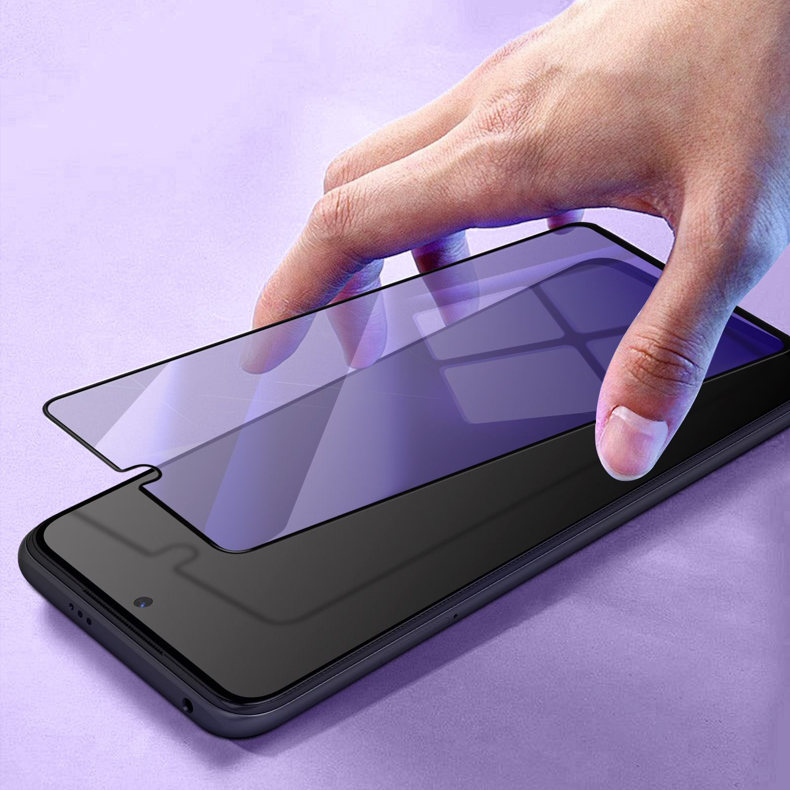 Una mano applica una protezione per lo schermo a uno smartphone nero. La scena è ambientata su uno sfondo viola.