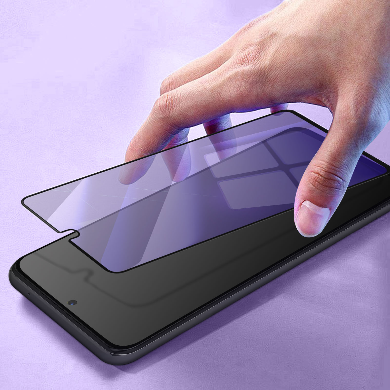 Una mano applica una protezione schermo su uno smartphone nero. Lo sfondo è una superficie viola strutturata.