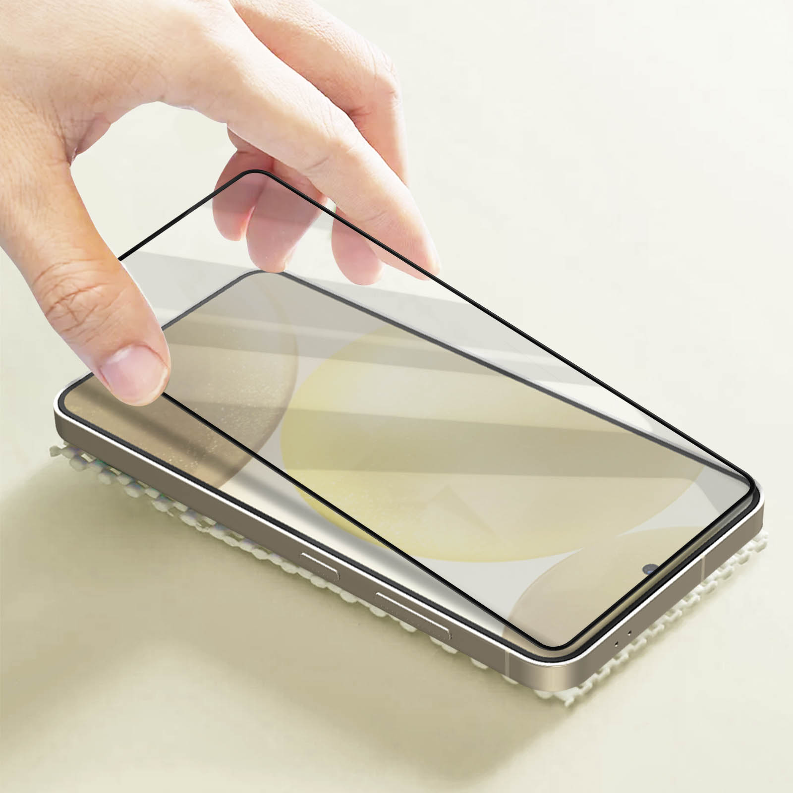 Mano che applica una protezione schermo a uno smartphone. Il telefono è su una superficie strutturata.