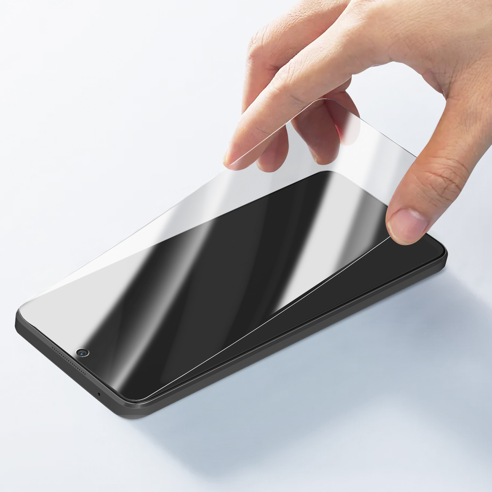Una mano sta applicando una protezione per lo schermo a uno smartphone nero. La protezione è trasparente e lo sfondo è bianco.