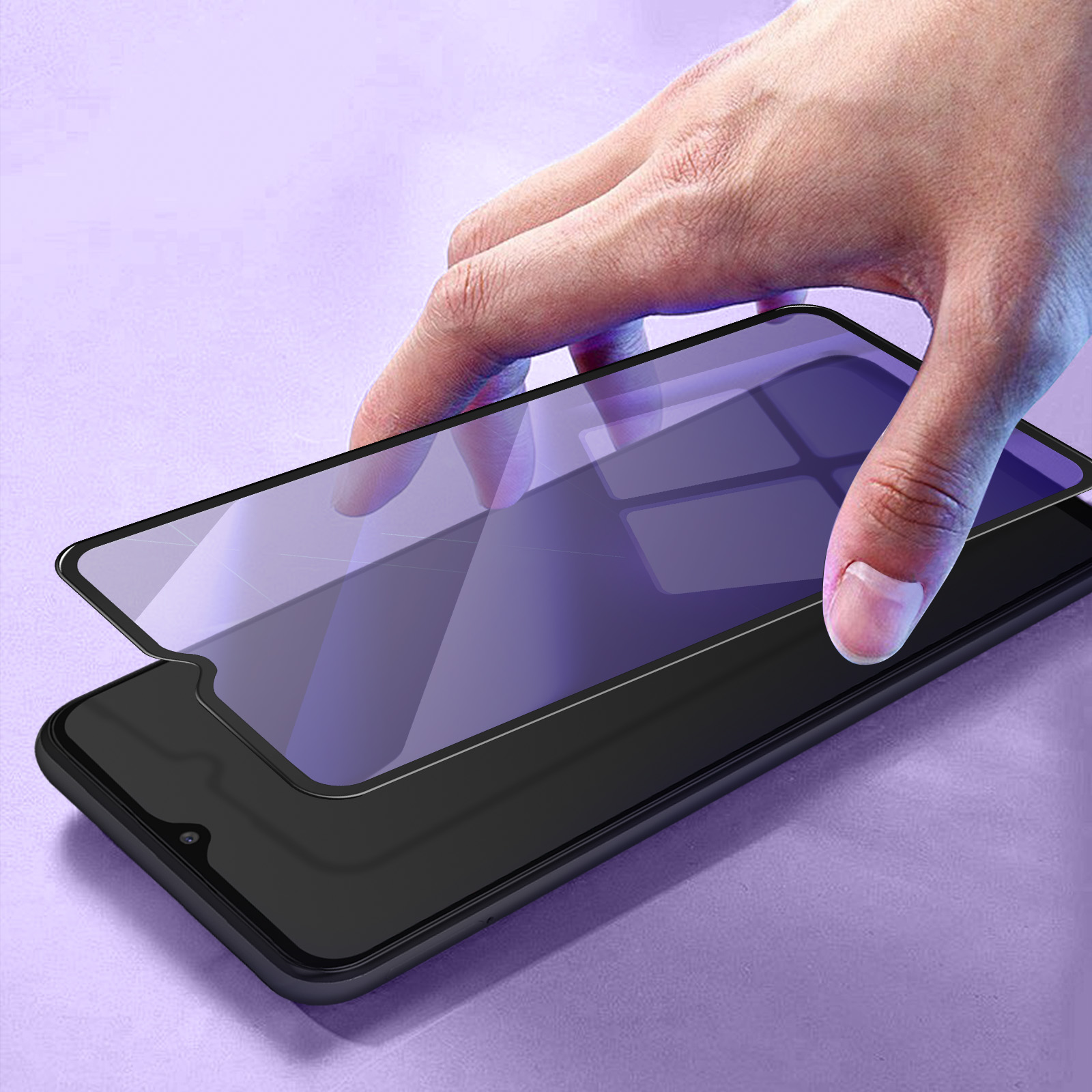 Una mano posiziona una protezione per lo schermo su uno smartphone nero. Lo sfondo è viola sfocato.