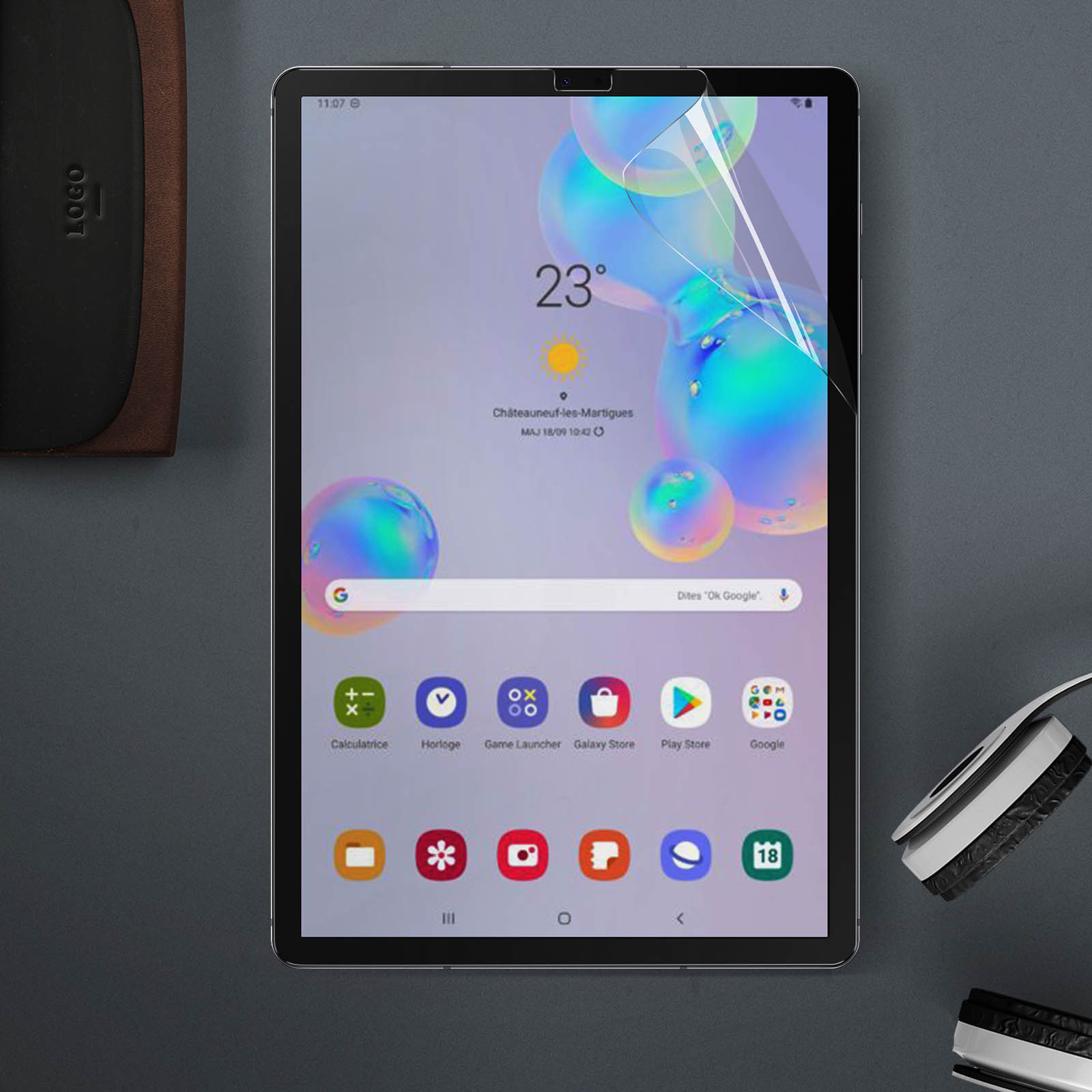 Schermo del tablet con informazioni meteo a 23 gradi. App: calcolatrice, orologio e Google. Pellicola protettiva visibile.