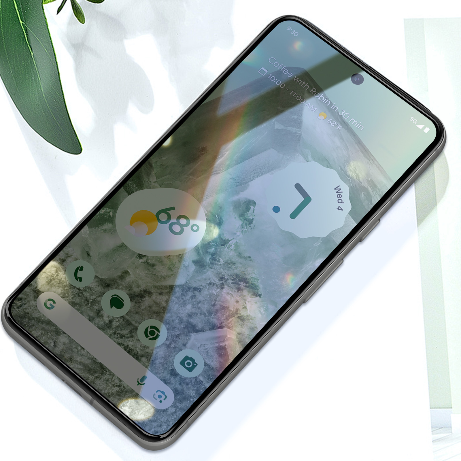 Uno smartphone mostra la schermata iniziale con icone di app, un widget meteo e un evento del calendario. Foglie verdi sullo sfondo.