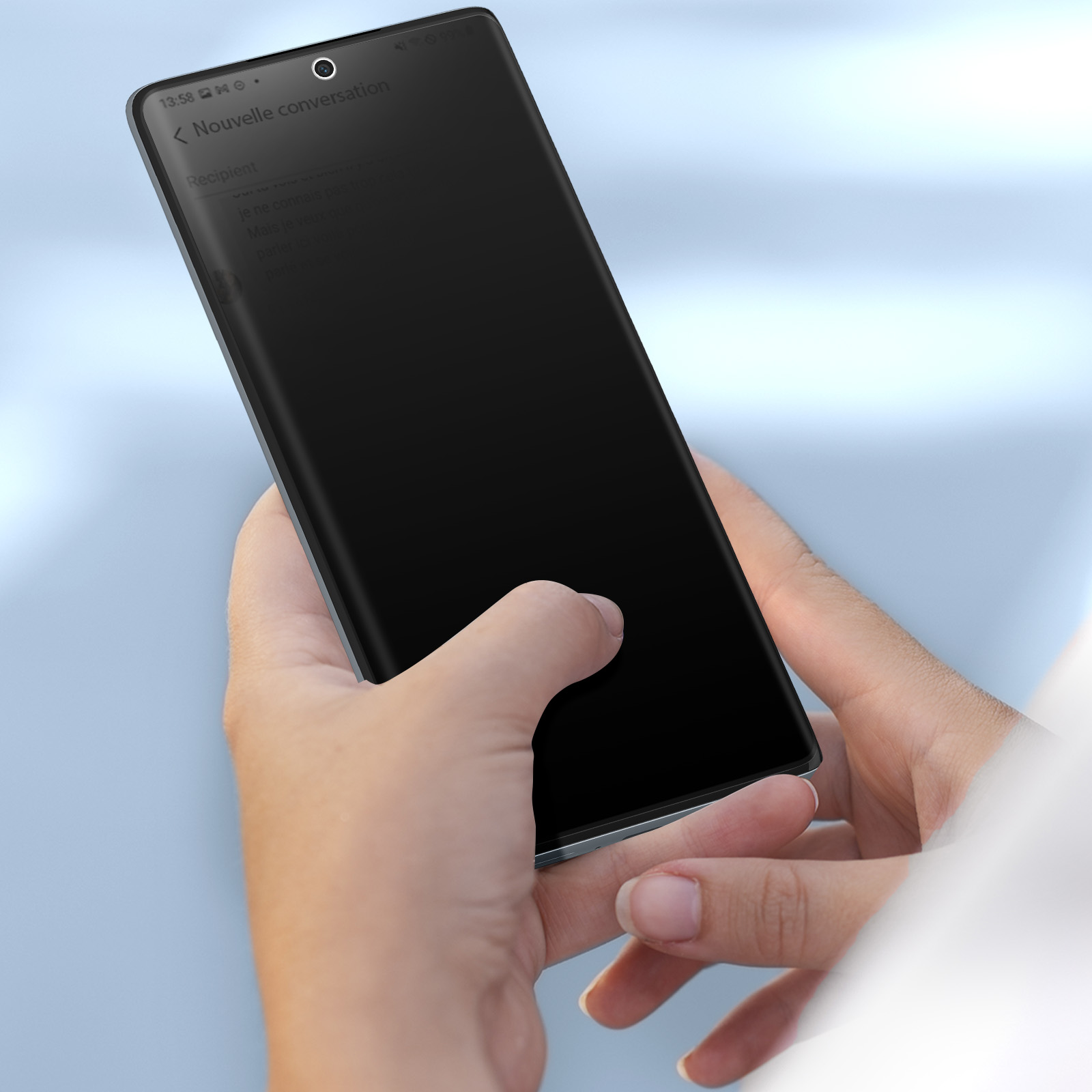 Mani che tengono uno smartphone nero che mostra una schermata di conversazione. Lo sfondo è una sfumatura blu chiaro.