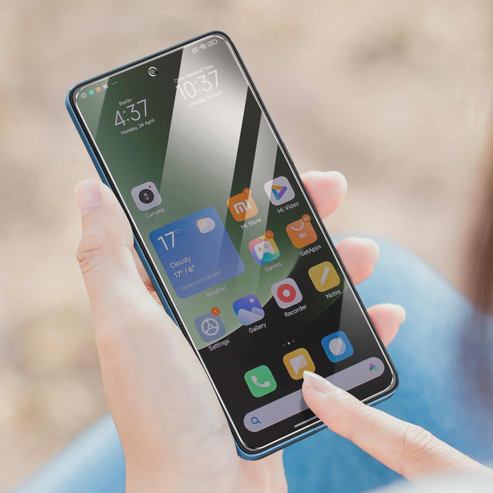 Una mano che tiene uno smartphone. Lo schermo mostra icone di app e l'ora. Il dito tocca un'icona. Lo sfondo è sfocato.