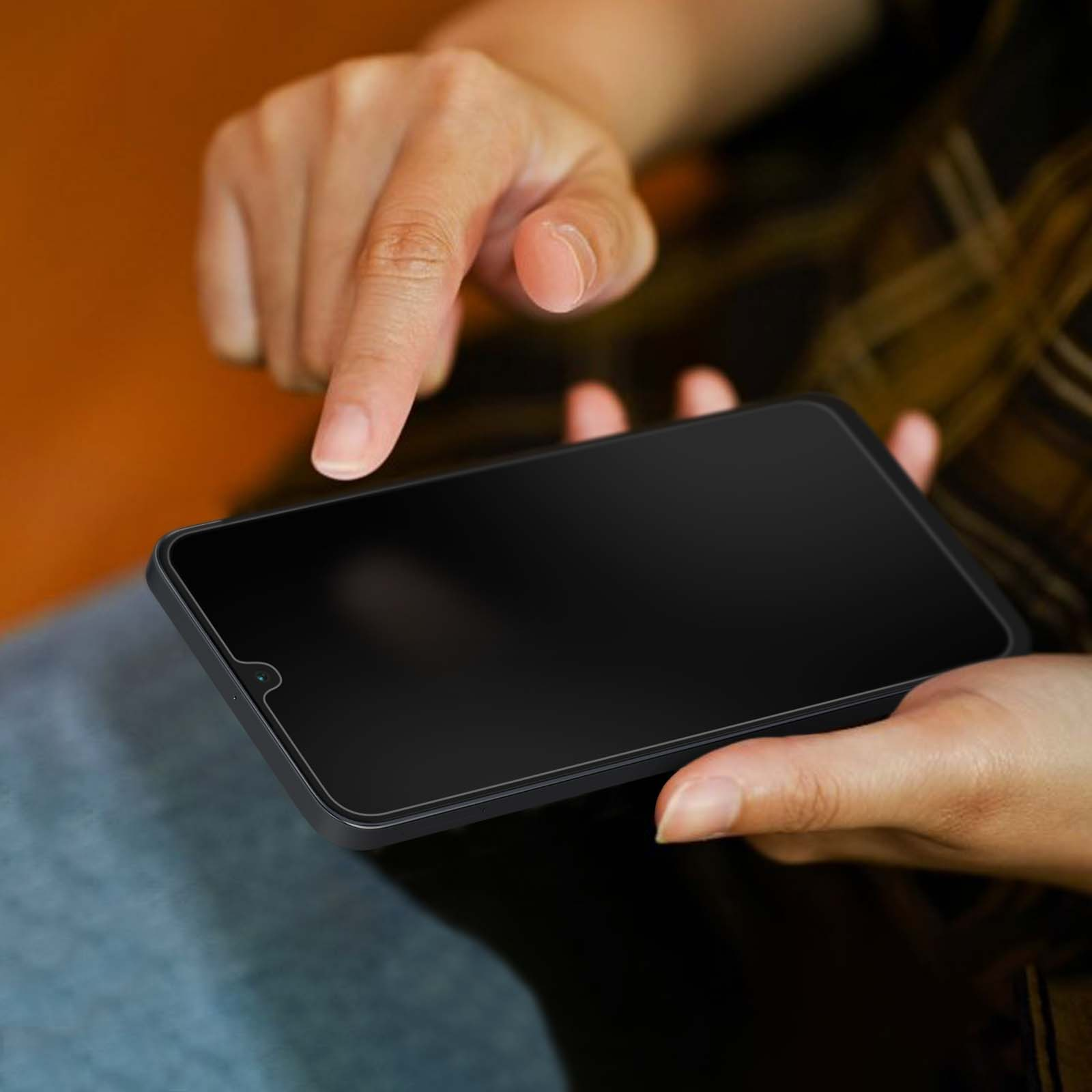 Mani che tengono uno smartphone nero. Un dito punta lo schermo. Lo sfondo è sfocato.