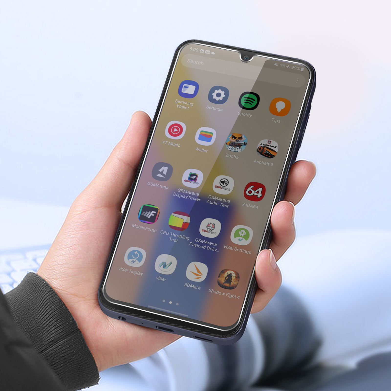 Una mano tiene in mano uno smartphone che mostra icone di app. Lo schermo mostra app come Spotify, Samsung Wallet e Asphalt 9.