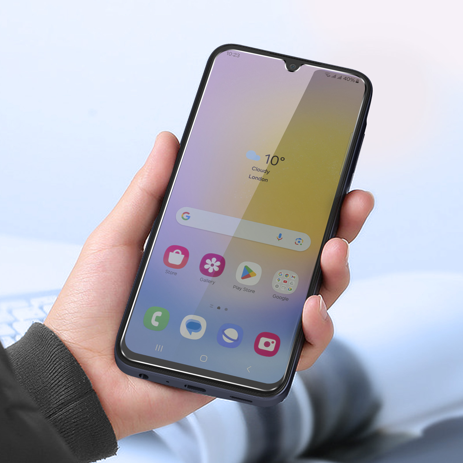 Mano che tiene uno smartphone nero con display che mostra app, meteo e ora. Lo sfondo è azzurro.