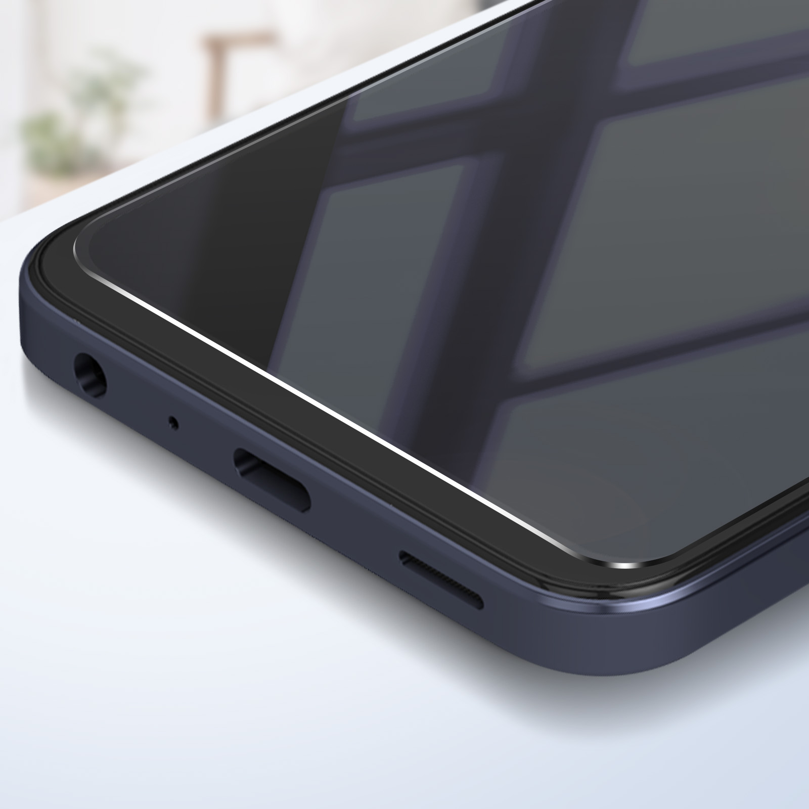 Primo piano di uno smartphone blu scuro. Lo schermo è nero e riflette la luce. Mostra il bordo con le porte e una superficie bianca.