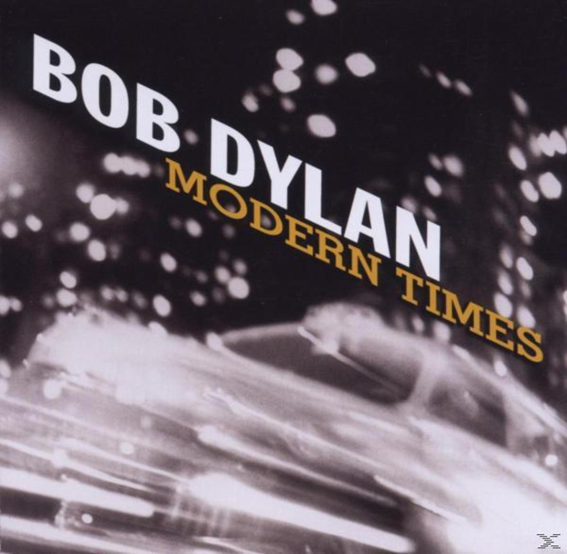 Copertina dell'album 'Modern Times' di Bob Dylan. Sfondo nero con testo bianco 'Bob Dylan' e oro 'Modern Times'. Immagine sfocata.
