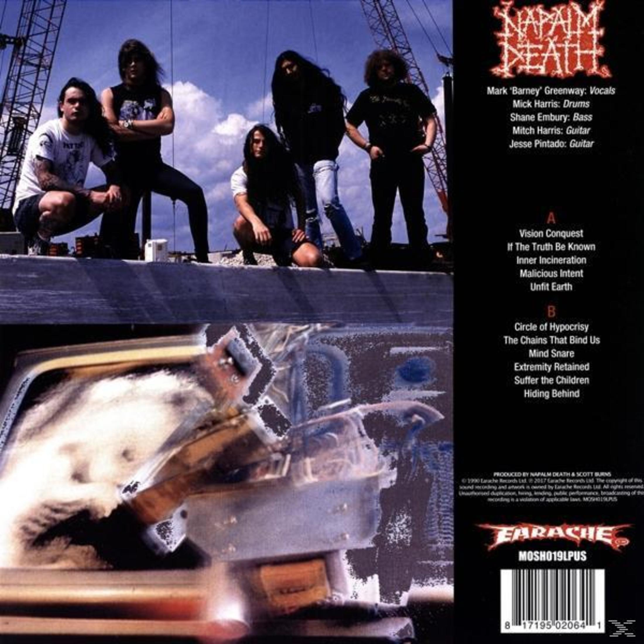 Bandmitglieder posieren, ein CD-Cover mit Titelliste und Credits befindet sich rechts, und eine beschädigte Metallstruktur im Vordergrund.