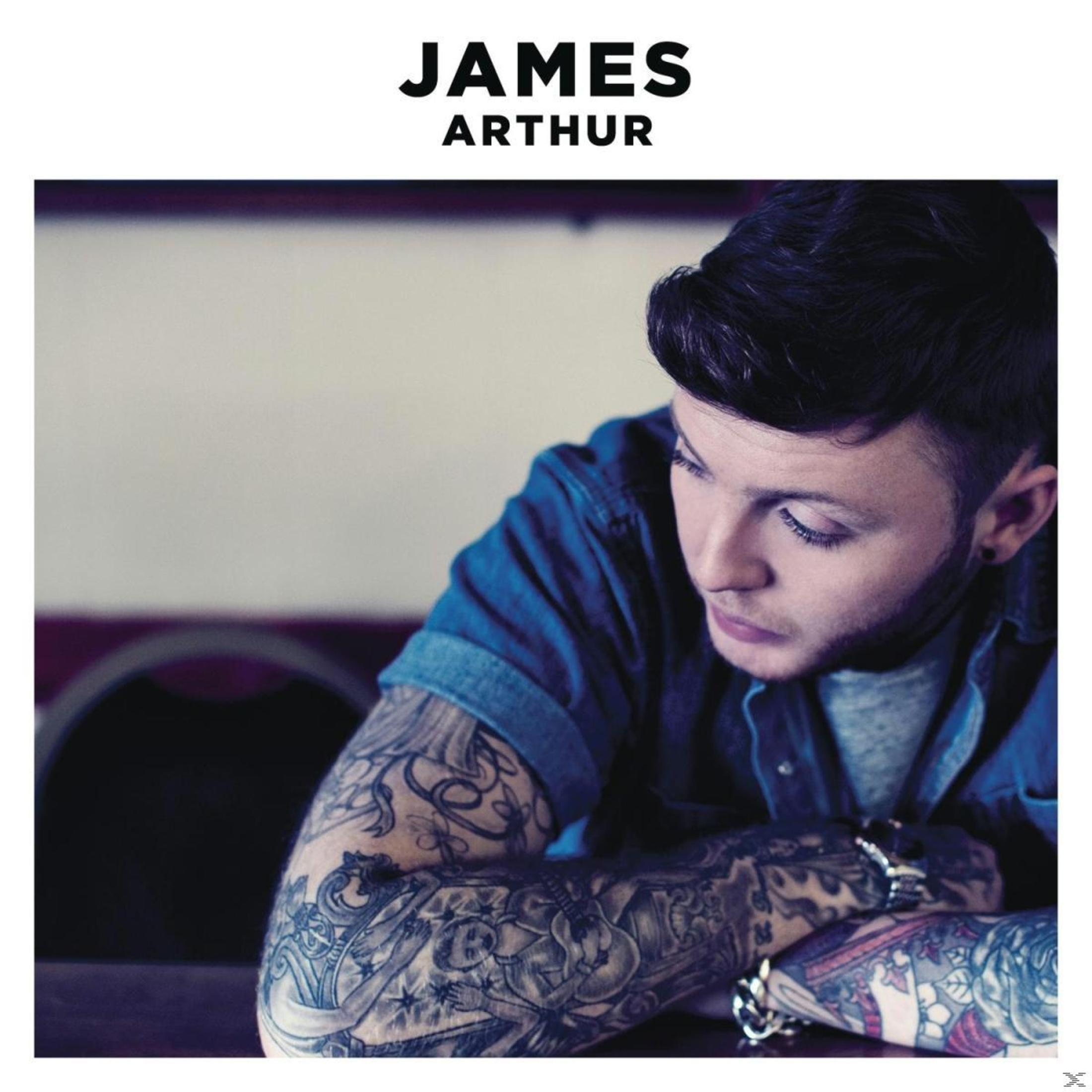 Copertina dell'album di James Arthur. Guarda in basso, indossa una camicia di jeans blu, con tatuaggi sul braccio. Il suo nome è in alto.