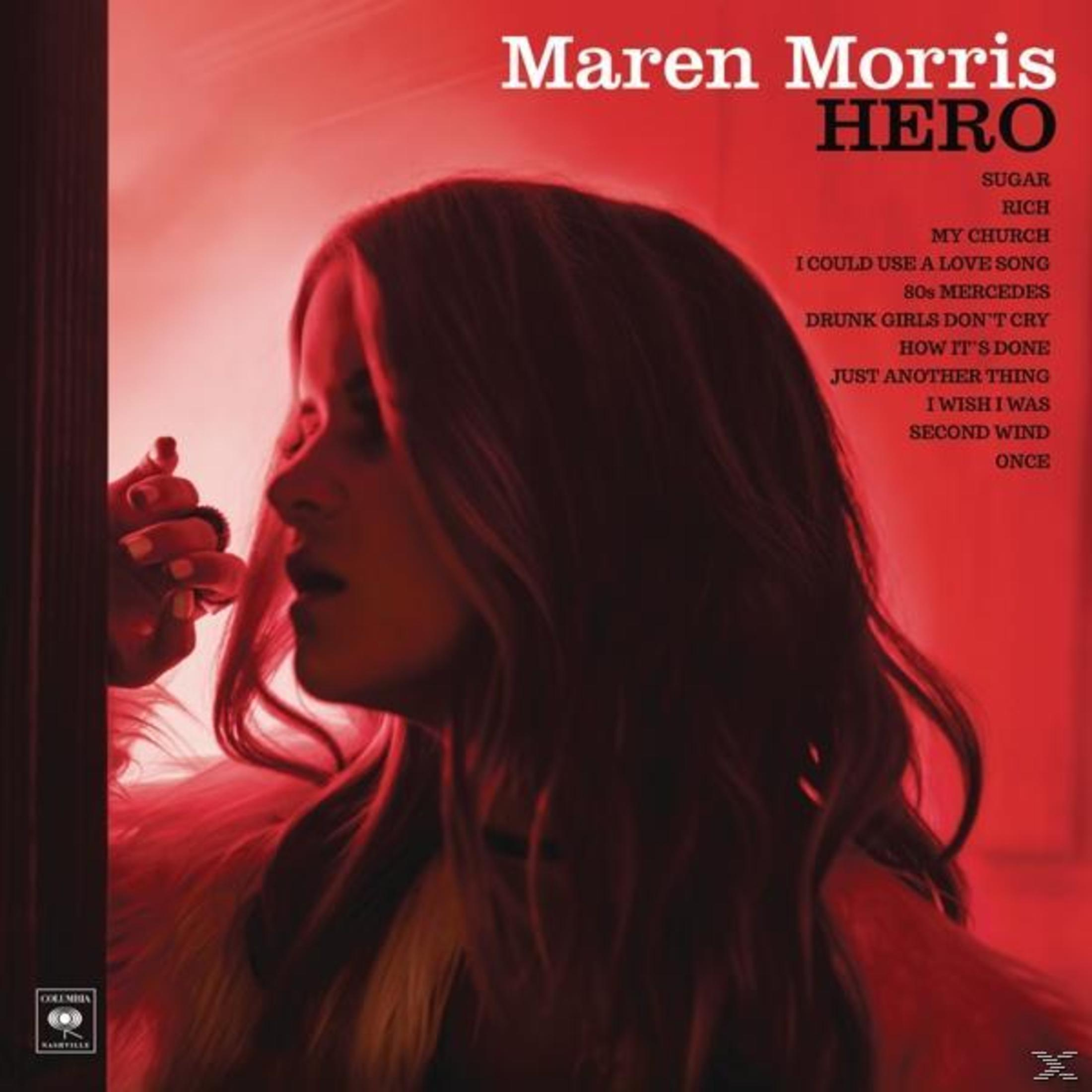 Albumhoes van Maren Morris' 'Hero'. Het toont een vrouwengezicht en tekst met songtitels op een rode achtergrond.