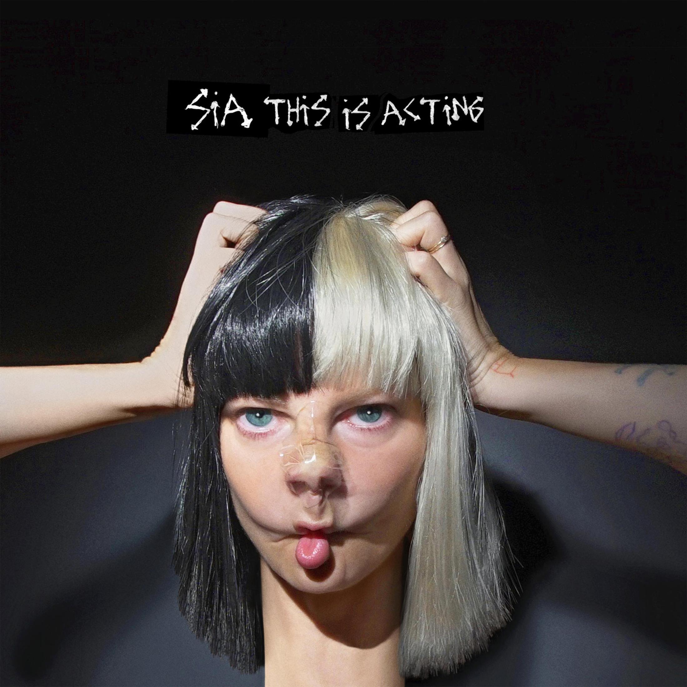 Sia con capelli bianchi e neri, indossa una copertura nasale trasparente, con la lingua di fuori e si tiene la testa. Lo sfondo è scuro.
