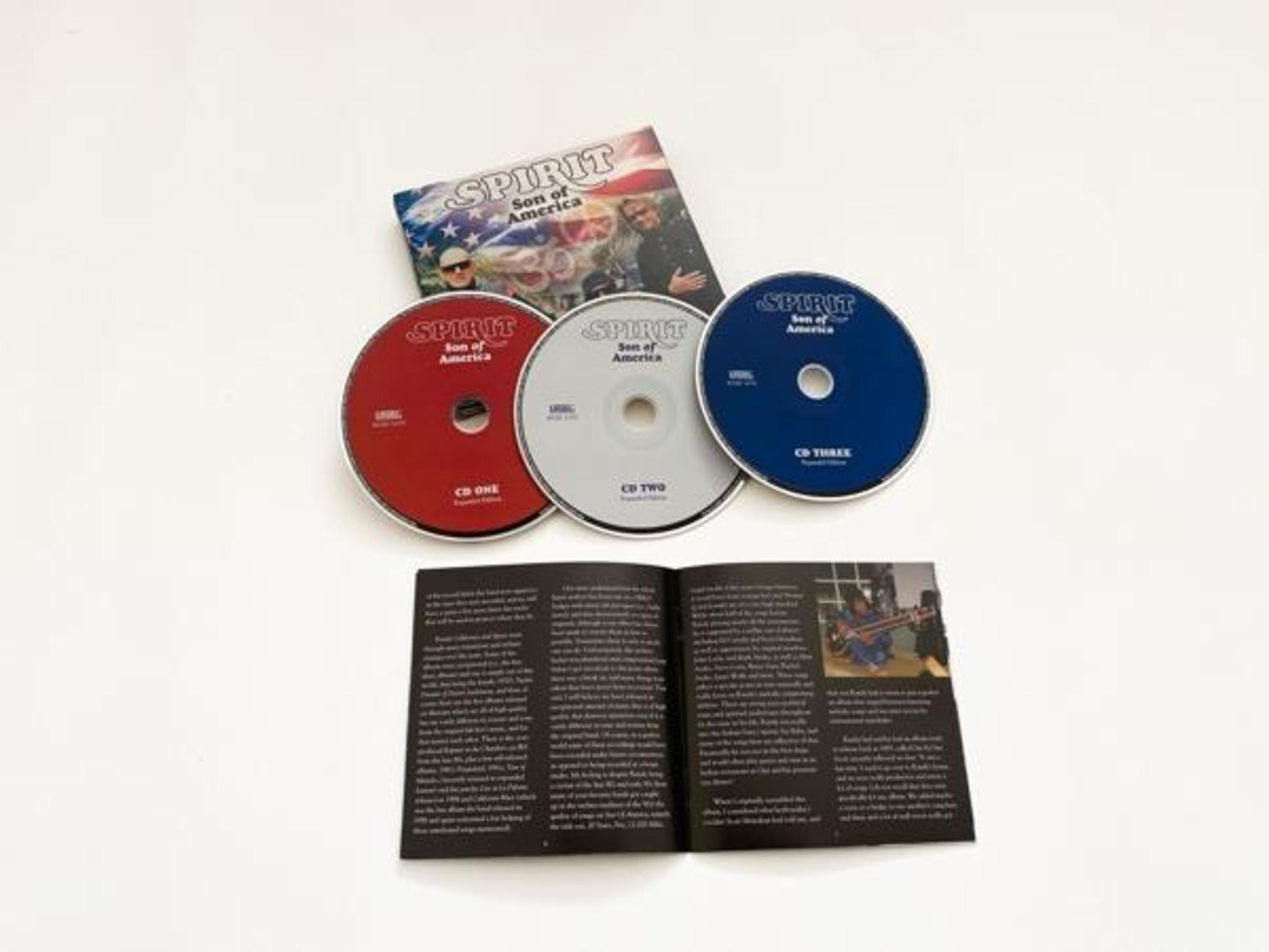 CD-Set mit drei Discs, einem Booklet und Cover. Die Discs sind rot, silber und blau. Das Cover hat eine Flagge.