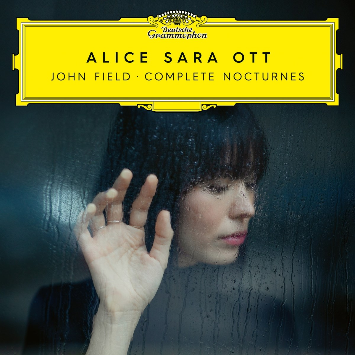 Donna tocca una finestra bagnata. Copertina dell'album: Alice Sara Ott, John Field, Complete Nocturnes. Logo Deutsche Grammophon.