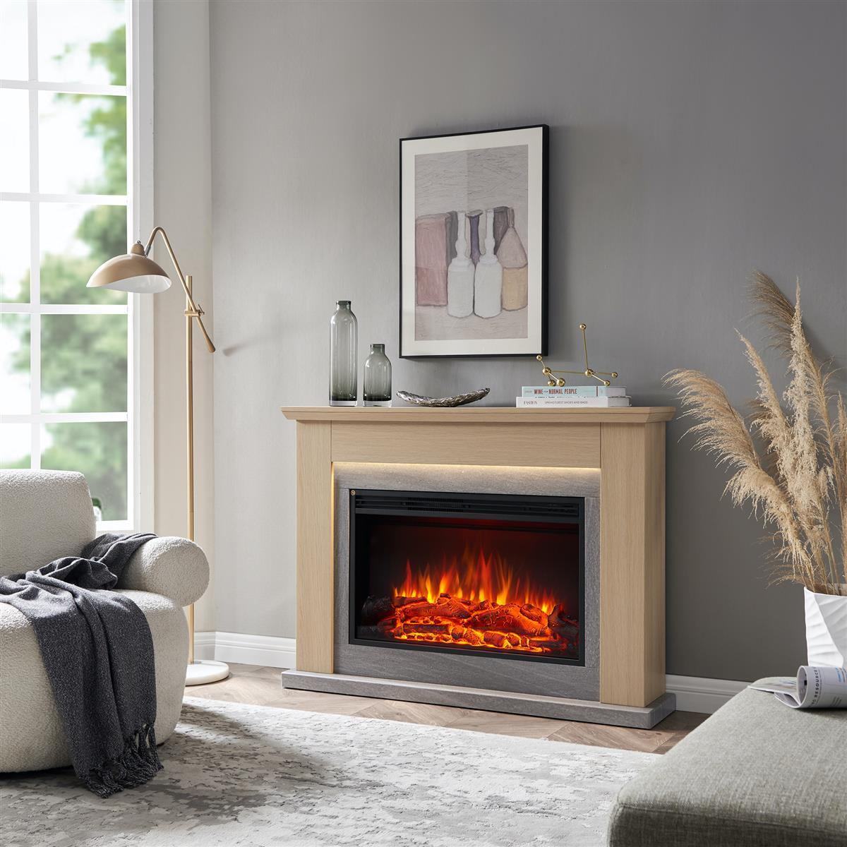 Ein Kamin mit leuchtendem Feuer, umrahmt von hellem Holz und Stein. Ein Gemälde von Flaschen hängt darüber. Im Vordergrund sind ein Sofa und ein Teppich.