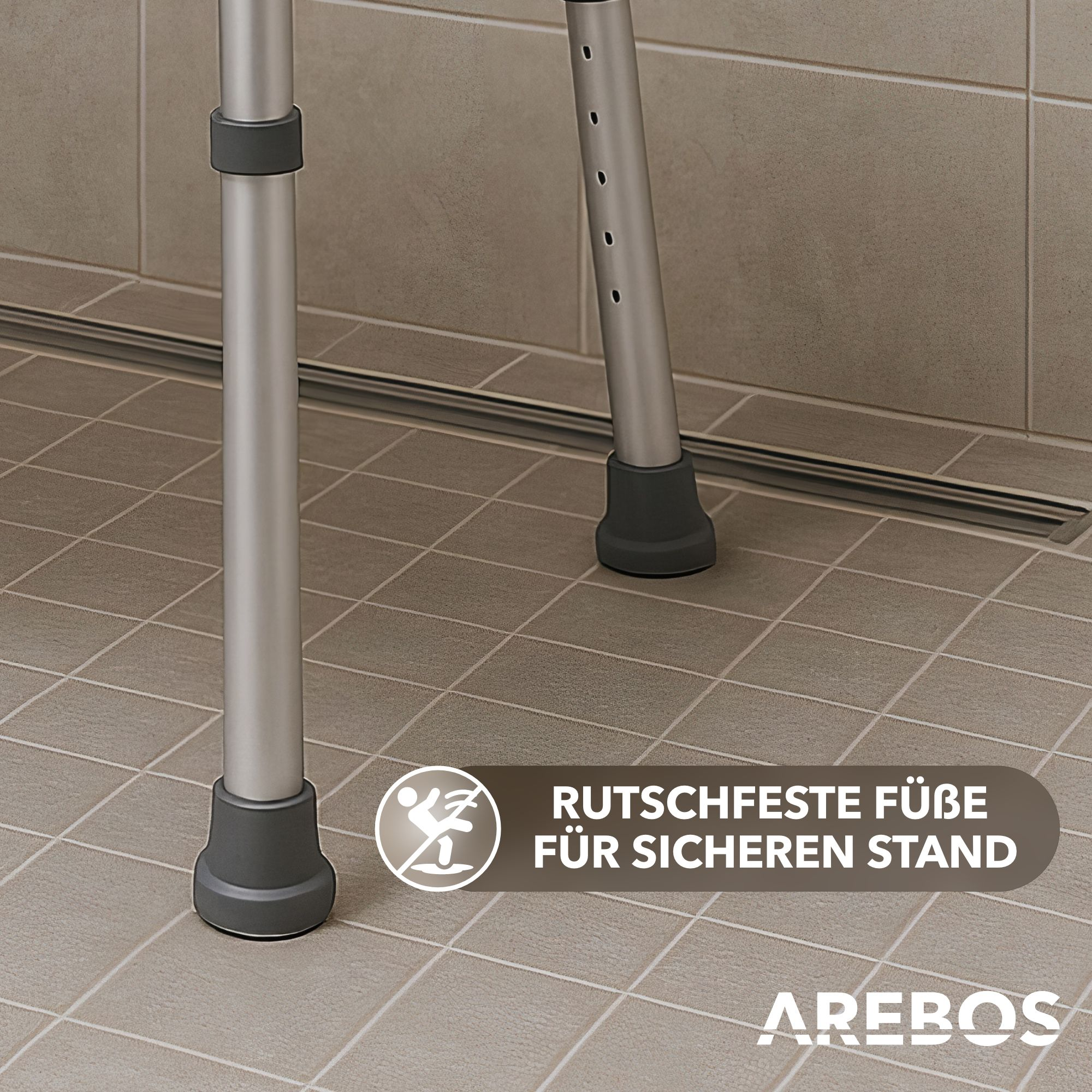 Silberne Beine eines Duschhockers auf Fliesenboden. Dunkelgraue Füße und schwarze Verbindungsringe. Text: Rutsfeste Füße für sicheren Stand.