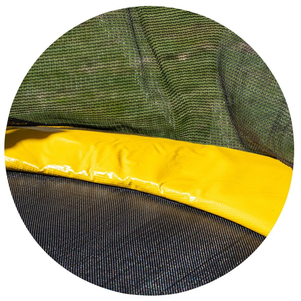Nahaufnahme eines Trampolins. Unten ein gelbes Polster, in der Mitte ein schwarzes Netz und im Hintergrund ein grünes Netz.