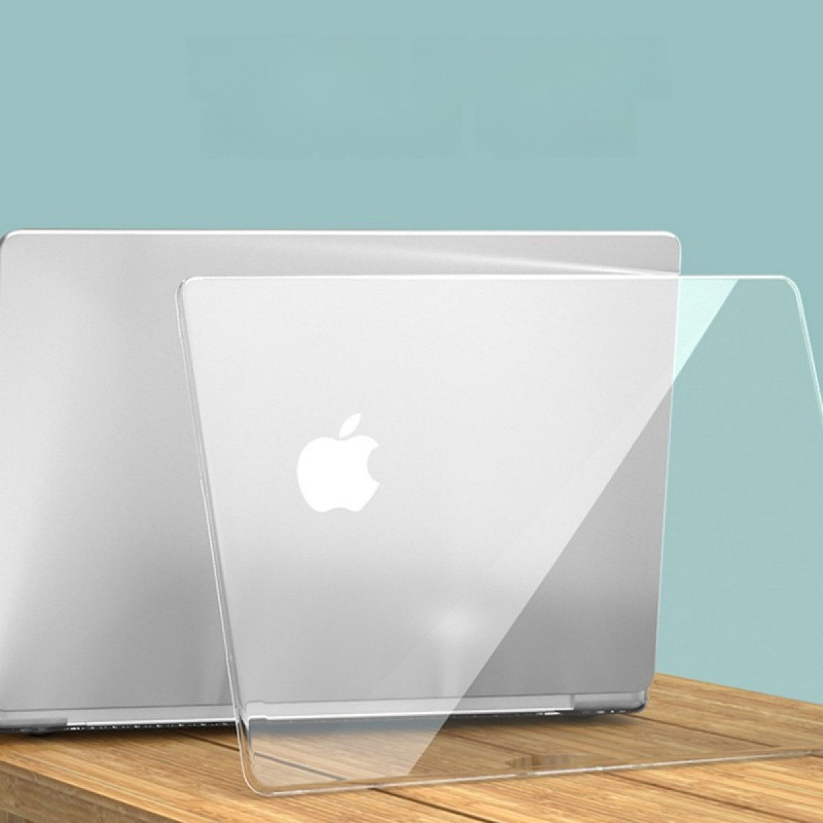 Ein silberner Laptop mit Apple-Logo, teilweise von einer transparenten Kunststoffhülle bedeckt, auf Holz.