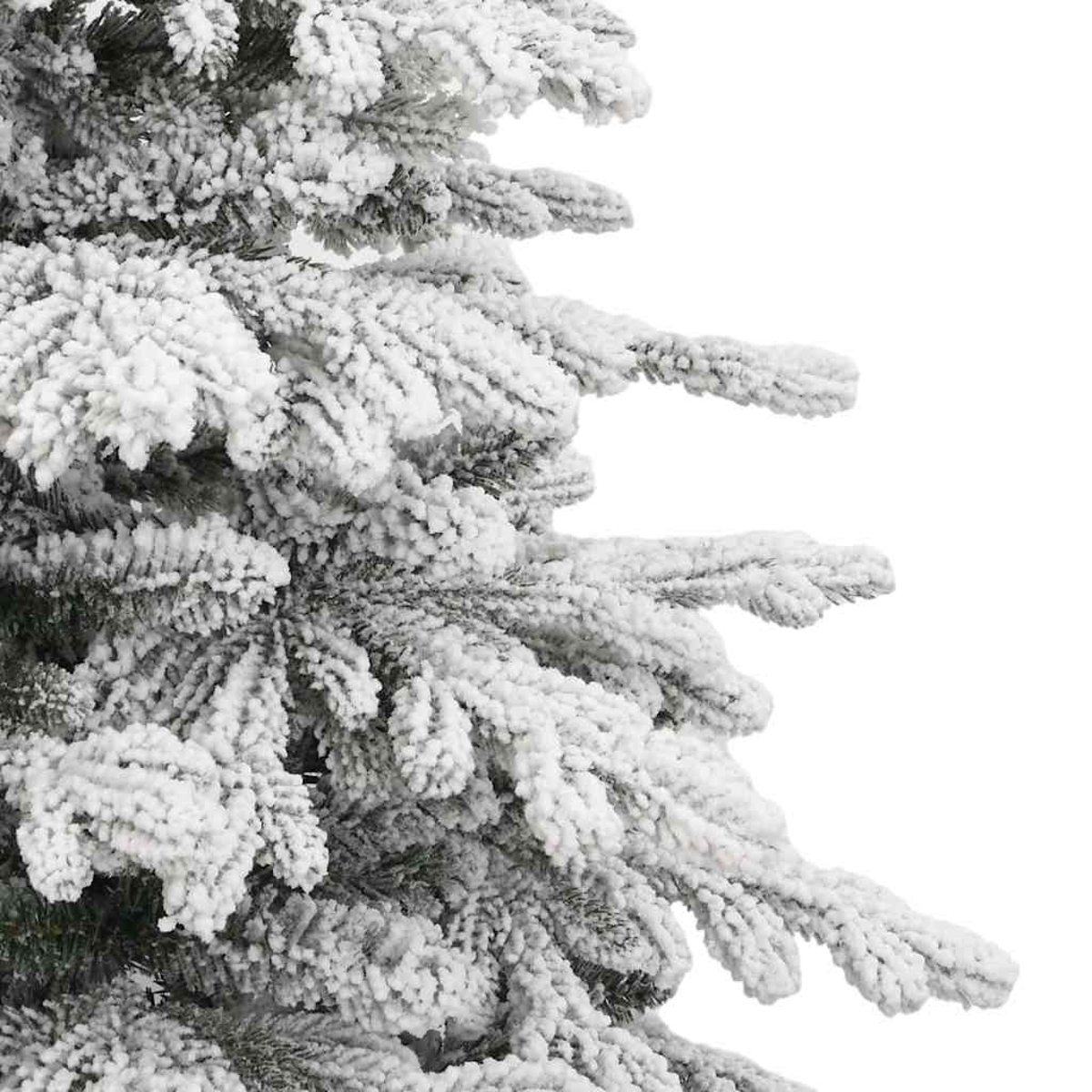 Nahaufnahme eines schneebedeckten Nadelbaums. Weißer Schnee bedeckt die Äste vor weißem Hintergrund. Grüne Nadeln blitzen hervor.