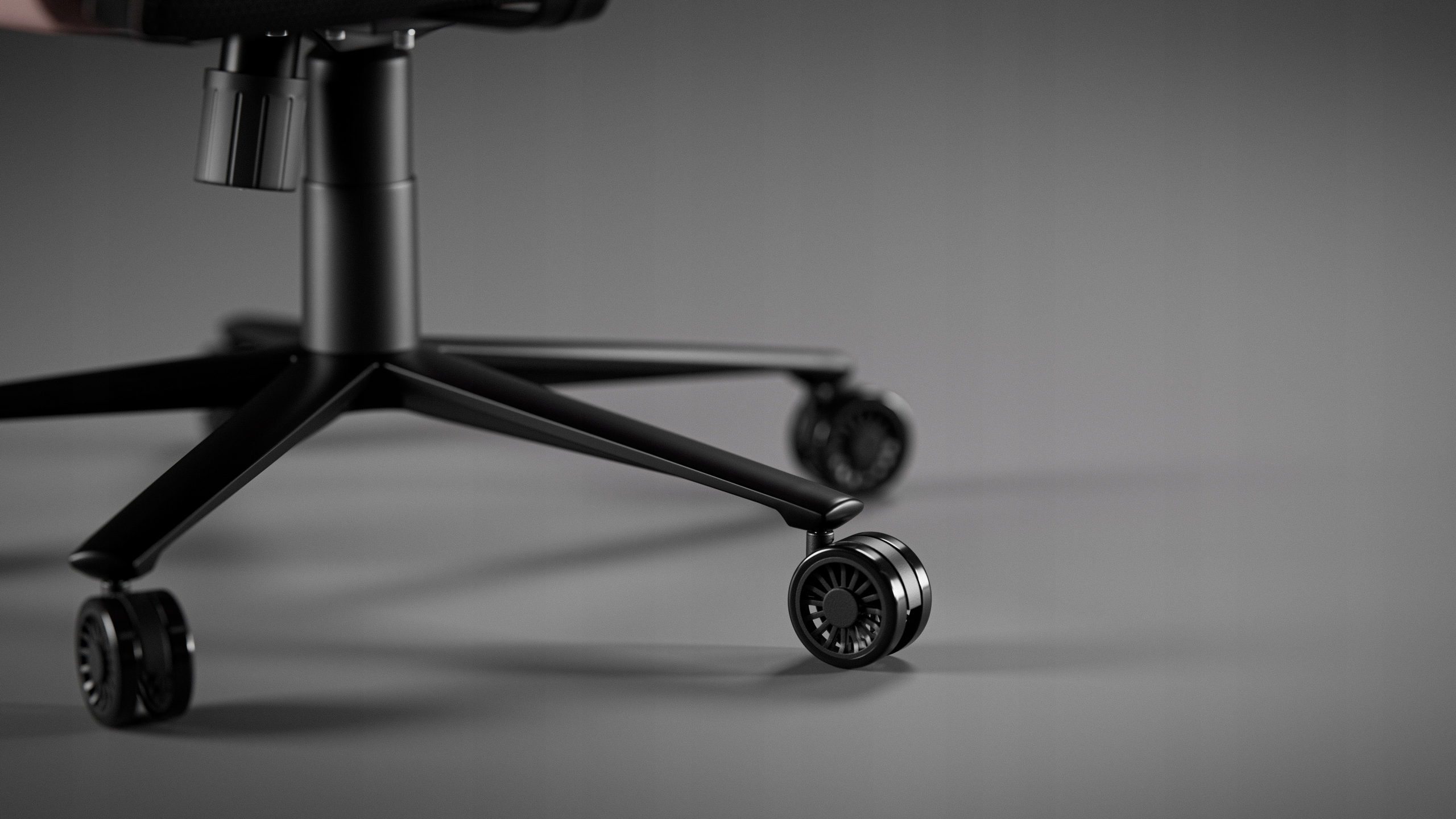 Zbliżenie czarnej podstawy krzesła biurowego z kółkami. Krzesło stoi na szarej powierzchni z szarym tłem.