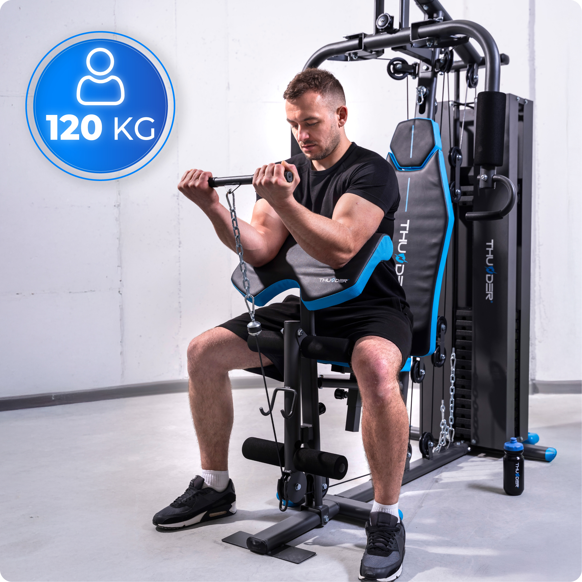 Mężczyzna używa maszyny do ćwiczeń z ciężarami, trzymając drążek. Niebieskie koło z ikoną osoby i '120 KG'. Czarne ubrania i buty.