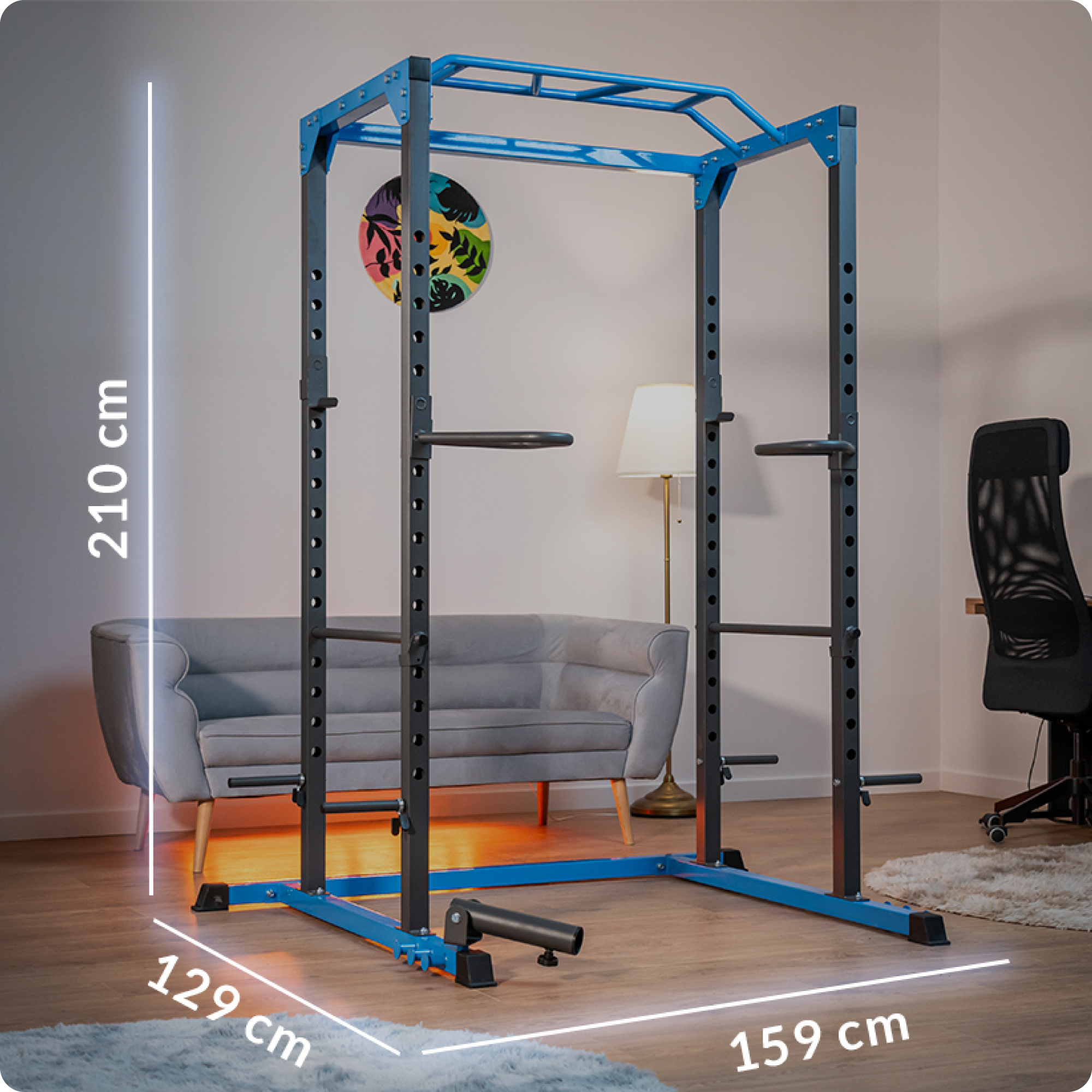 Niebiesko-czarny stojak do podnoszenia ciężarów stoi w pokoju. Widoczne są również sofa, lampa, dywan i krzesło.