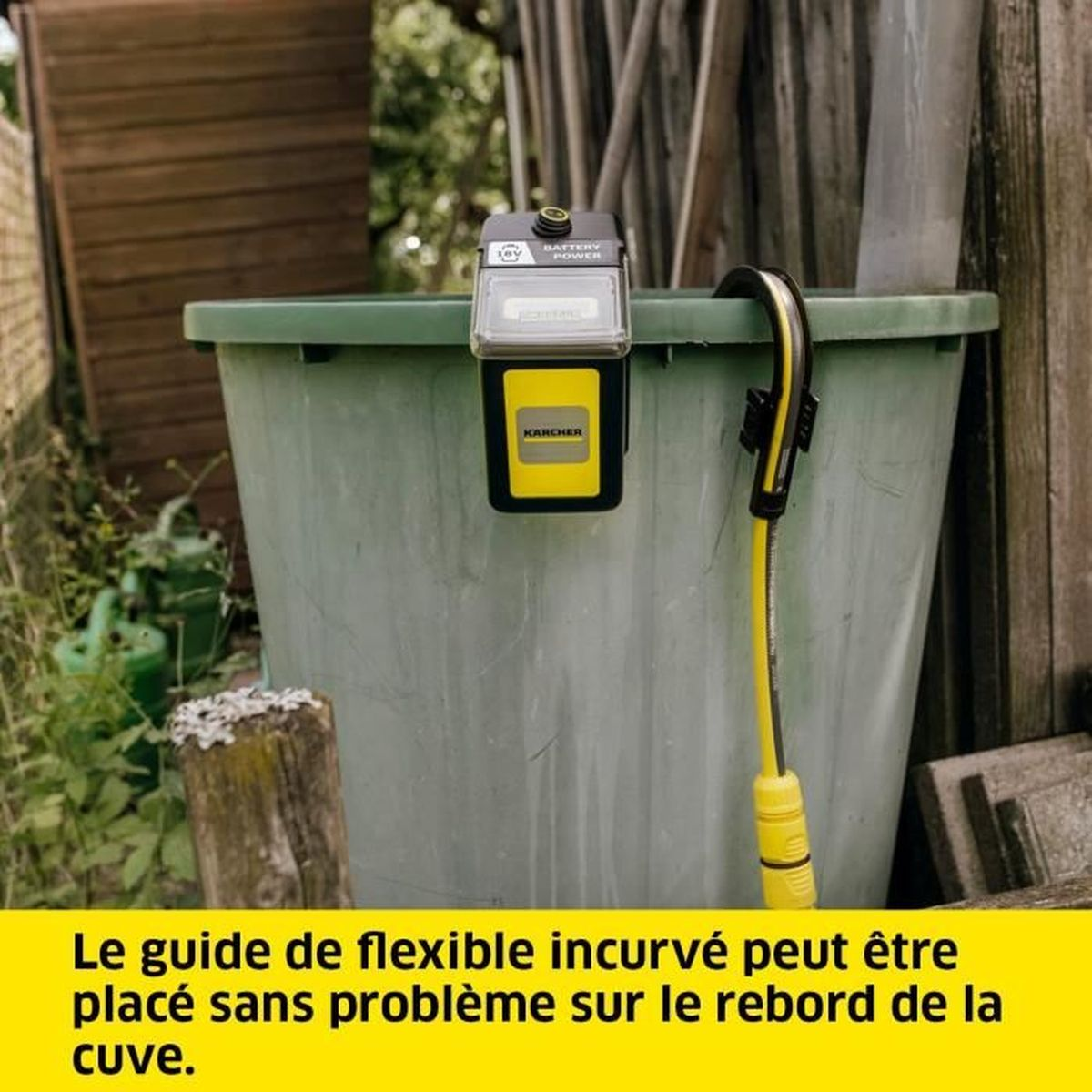 Un dispositivo Karcher negro y amarillo con batería está conectado a un contenedor verde, con una manguera amarilla colgando del lado.