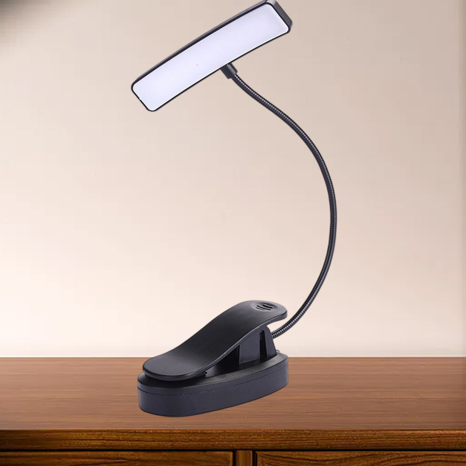 Schwarze LED-Leselampe zum Anklemmen auf einer Holzoberfläche. Die Lampe hat einen biegsamen Hals und ein rechteckiges Licht.