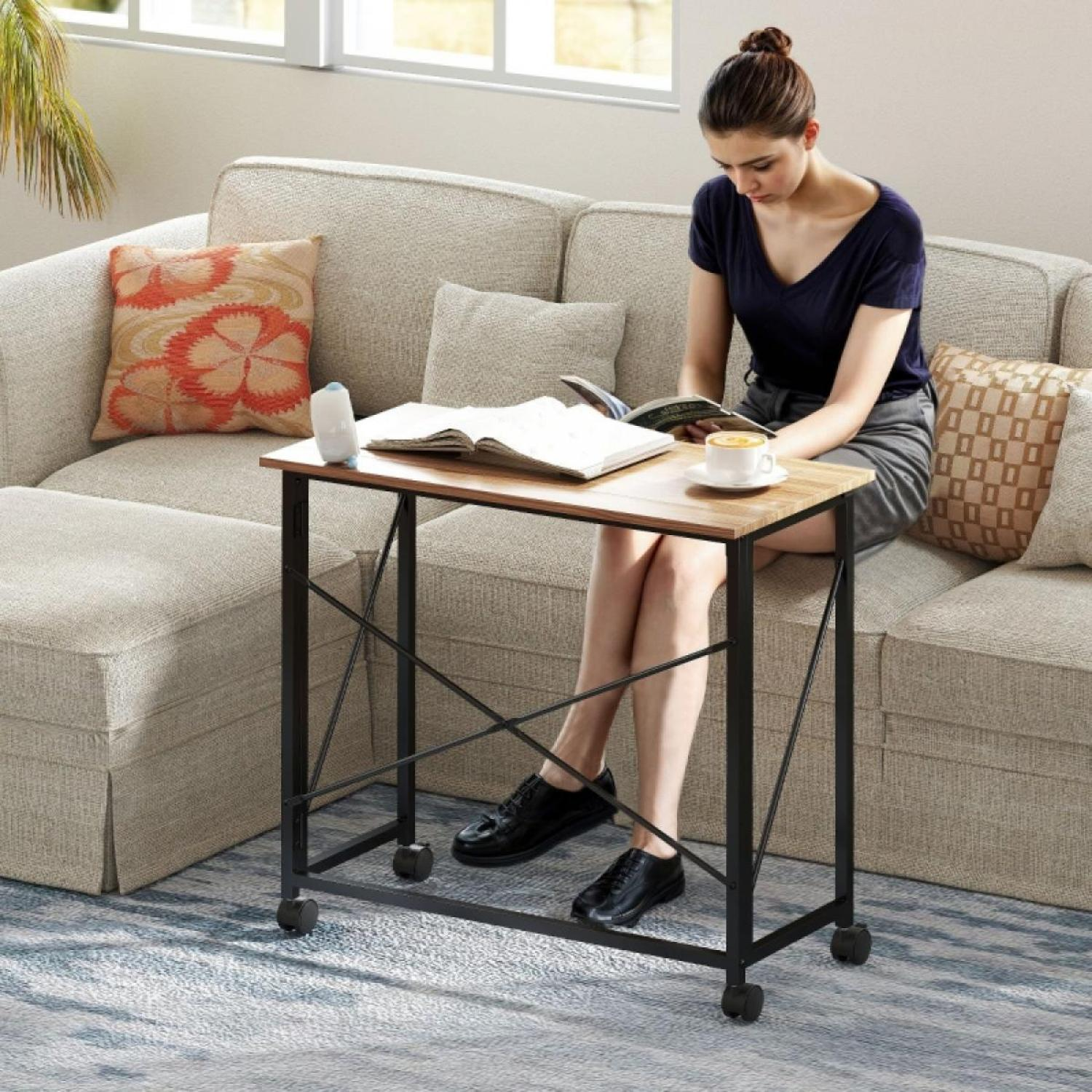 Frau liest auf einem Sofa. Vor ihr steht ein Tisch mit Buch und Kaffee. Kissen und ein Fenster sind im Hintergrund.